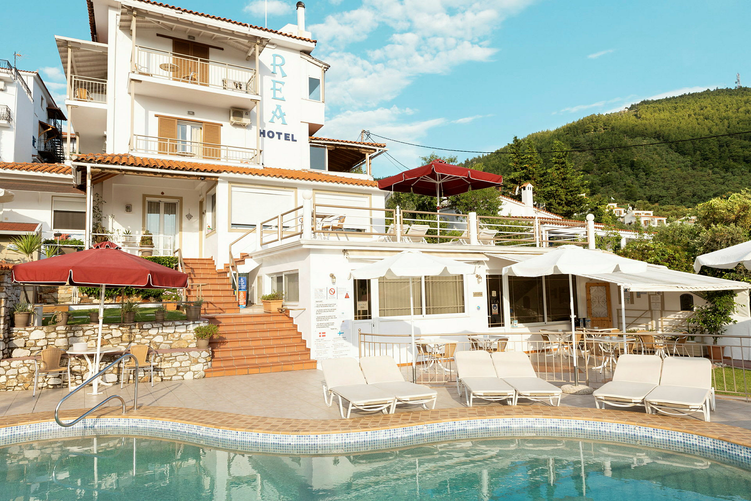 En hotellbyggnad med flera nivåer och en pool i förgrunden. (AI-genererad text)