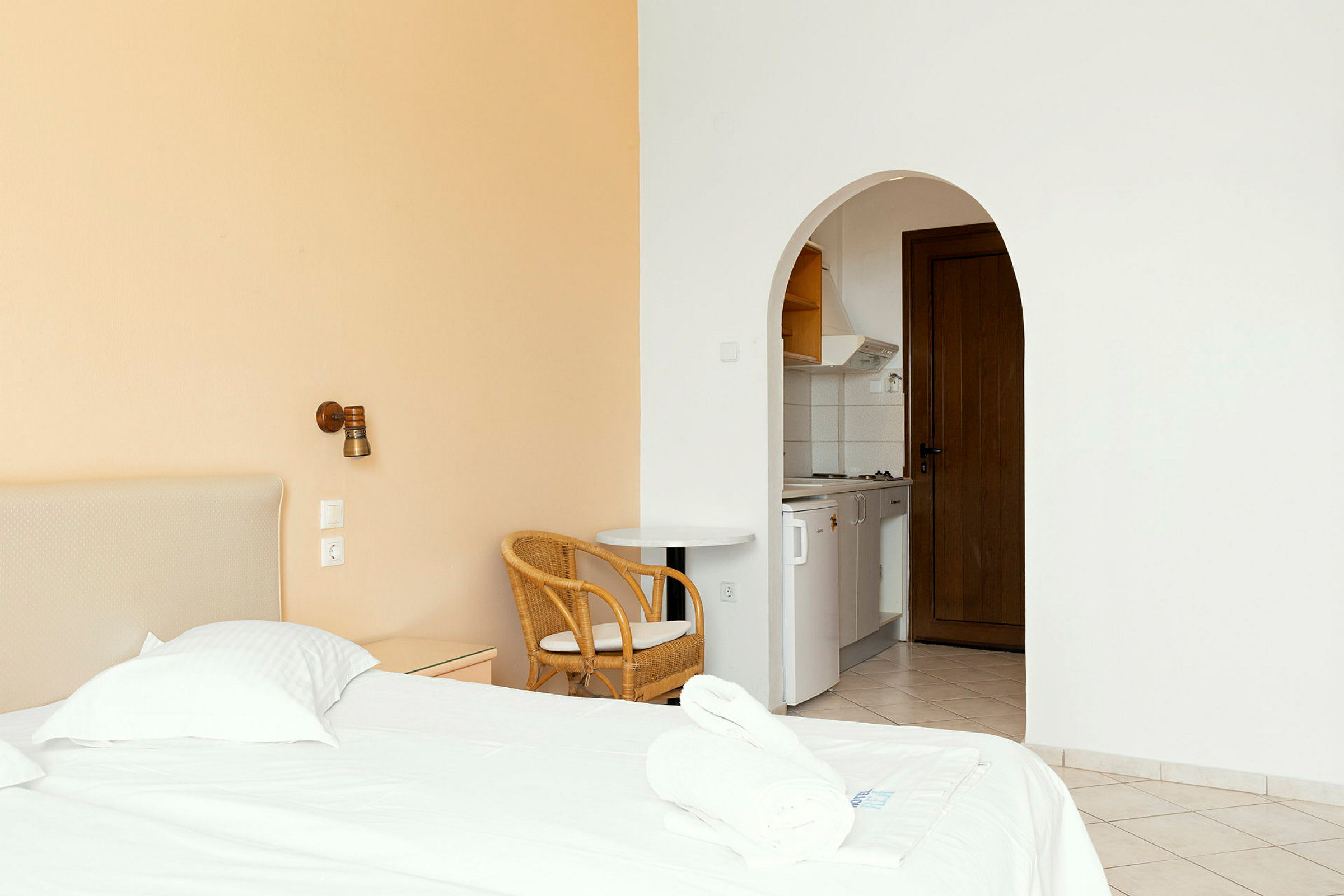 Ett hotellrum med en säng, stol och ett öppet kök. (AI-genererad text)
