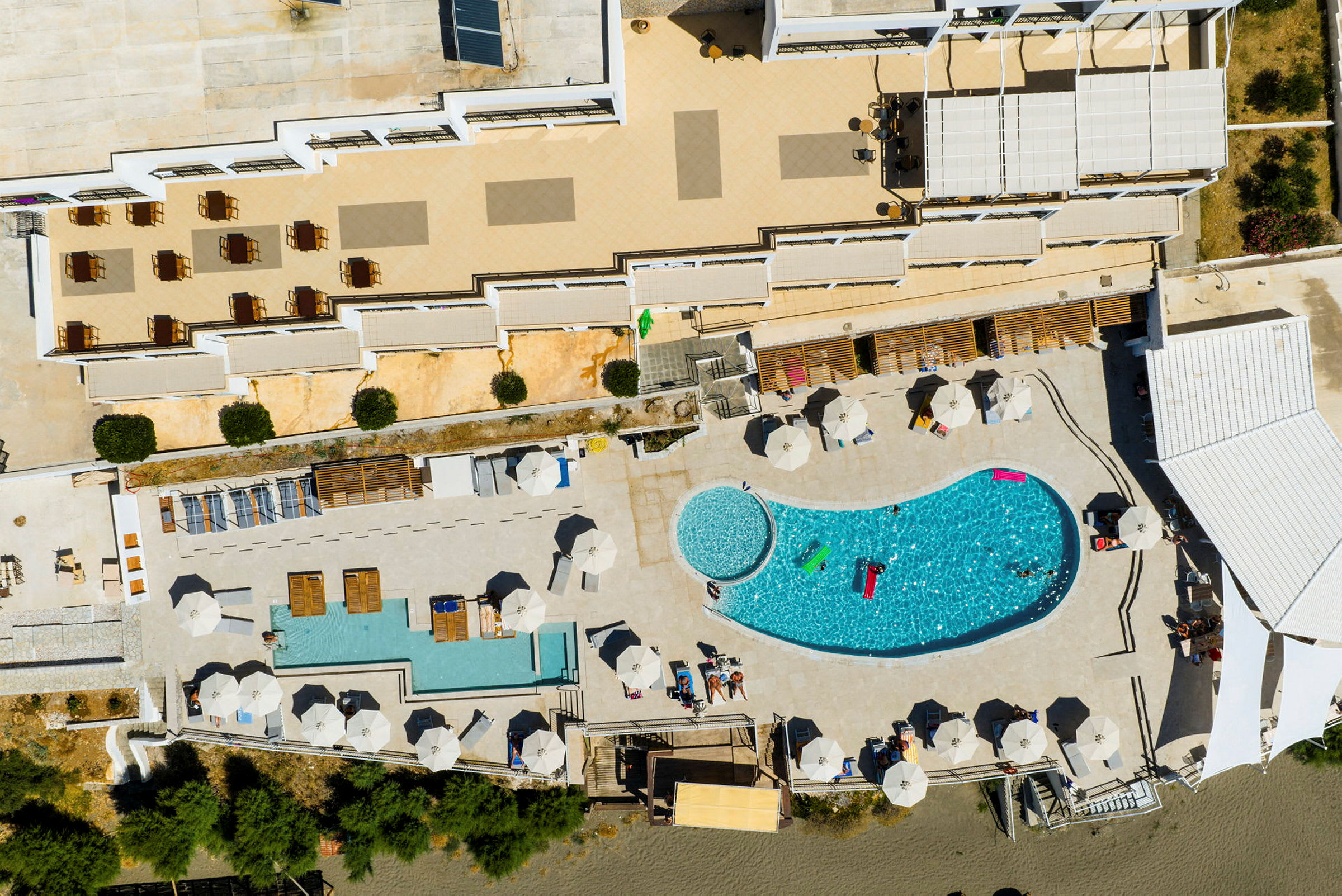 Luftfoto av ett hotellområde med en pool, solstolar och parasoller. (AI-genererad text)