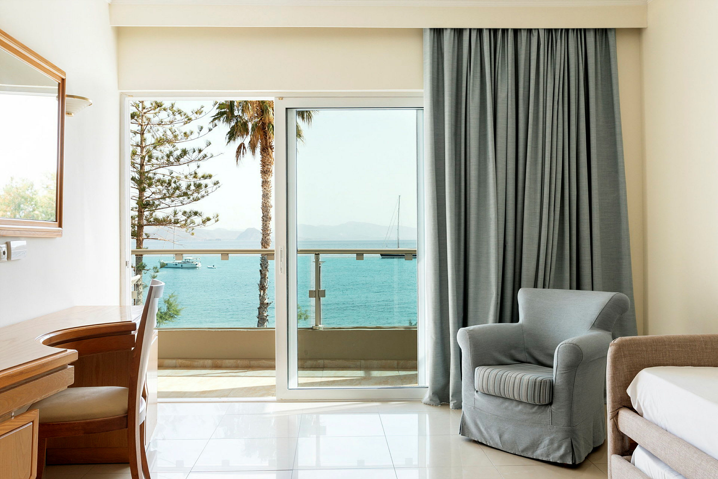 Ett hotellrum med utsikt över havet genom glasdörrar. (AI-genererad text)