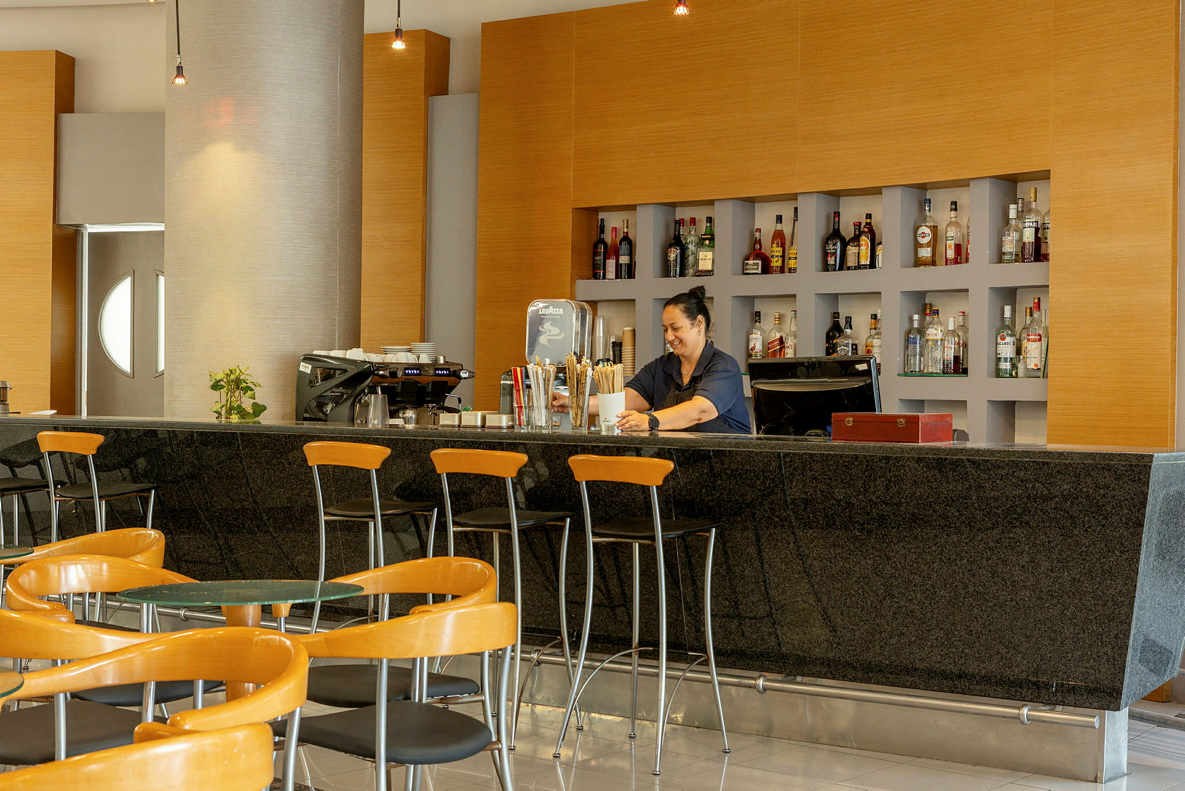 En hotellbar med sittområde och hyllor fyllda med flaskor. (AI-genererad text)