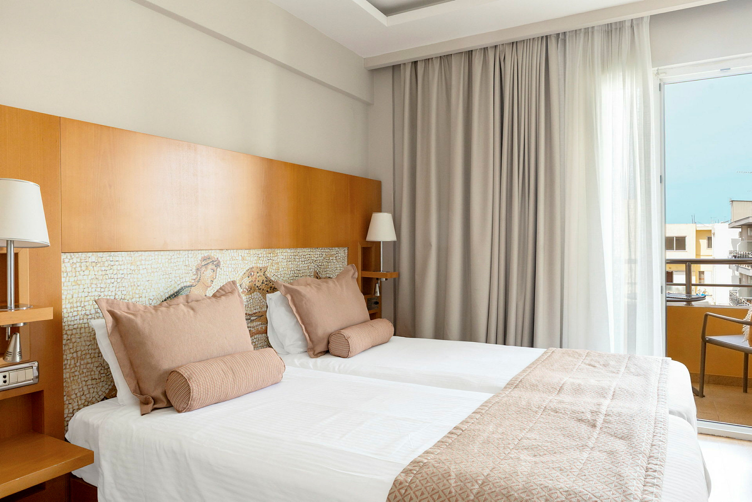 Två bäddar i ett hotellrum med ljusa textiler och trädetaljer. (AI-genererad text)