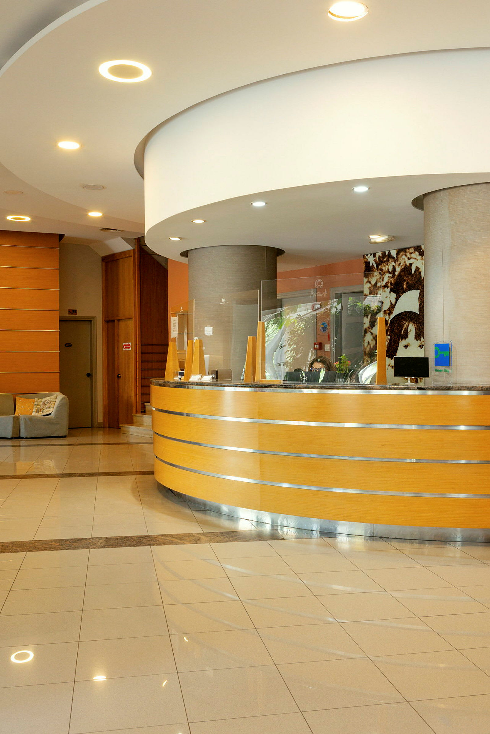 En receptionsdisk i trä med dekorativ belysning och glasdetaljer i en hotellobby. (AI-genererad text)