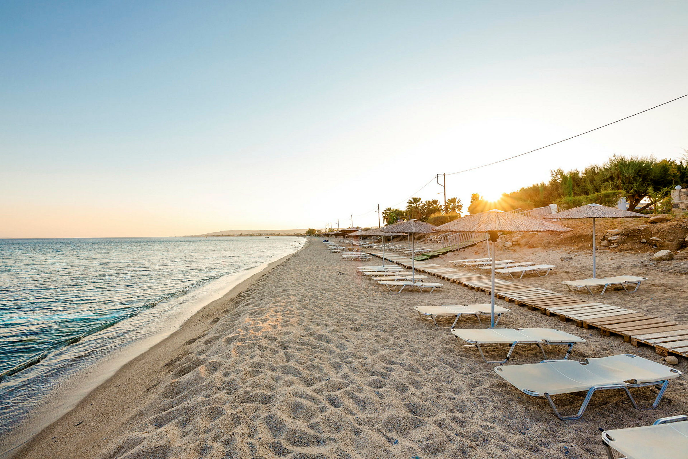 Strand med solstolar och parasoller vid solnedgången. (AI-genererad text)