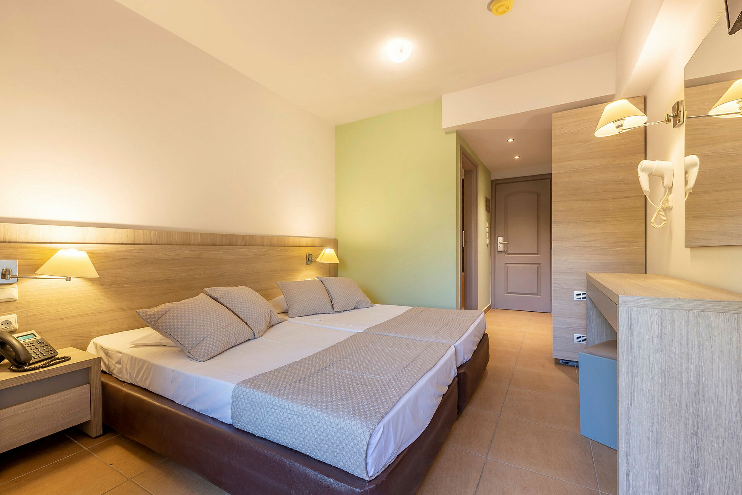 Hotellrum med två enkelsängar, lampor och skrivbord. (AI-genererad text)