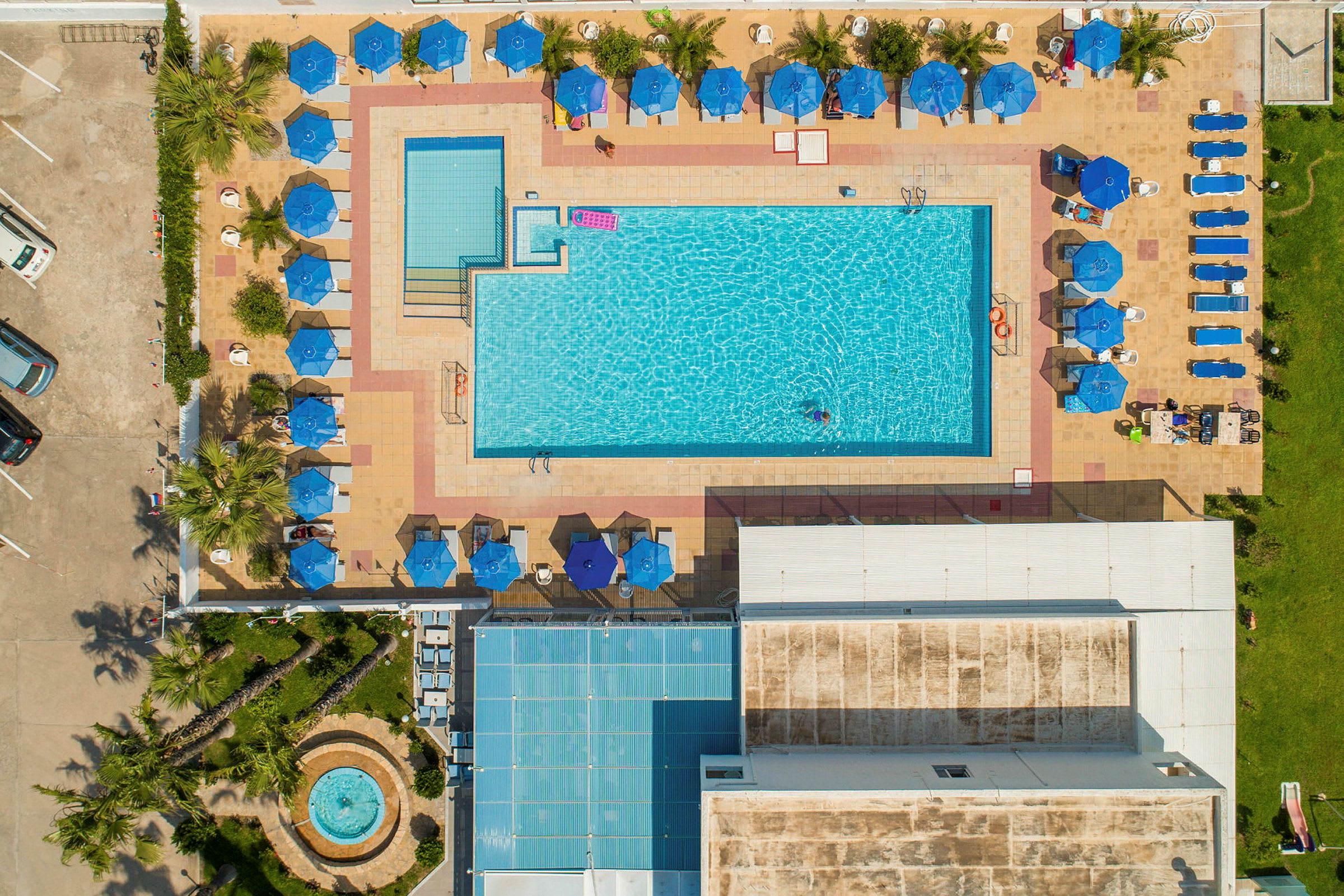 Flygbild av en poolområde med solstolar och parasoller runt poolen. (AI-genererad text)