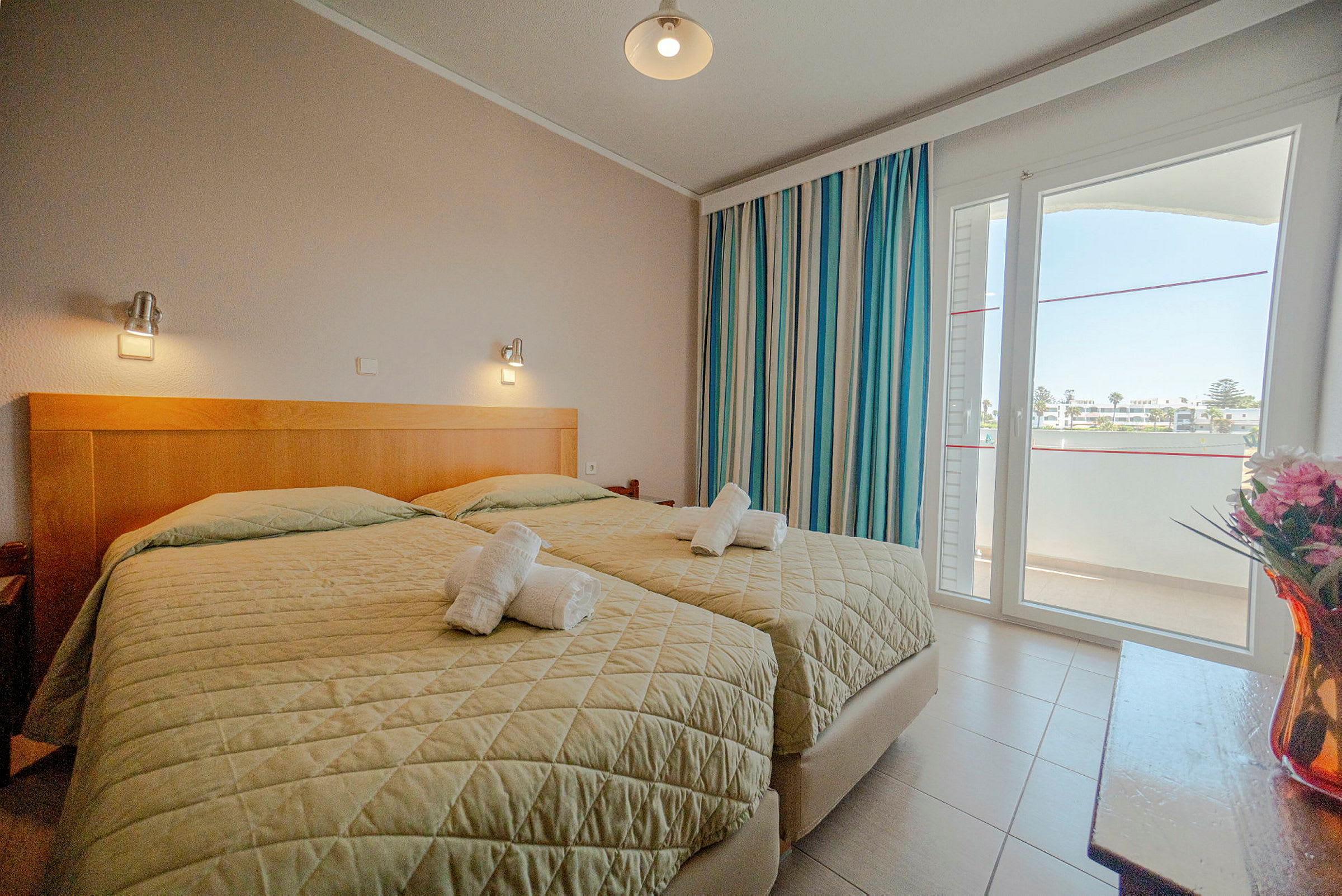 Ett hotellrum med två enkelsängar, fönster och dekorationer. (AI-genererad text)