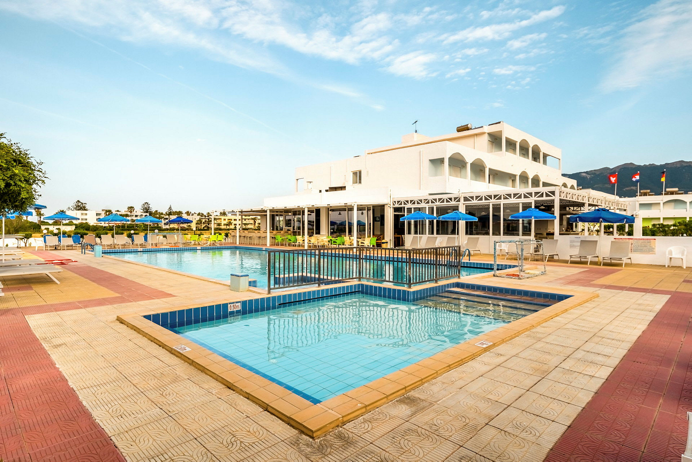 En utomhuspool omgiven av solstolar och parasoll vid ett hotell. (AI-genererad text)