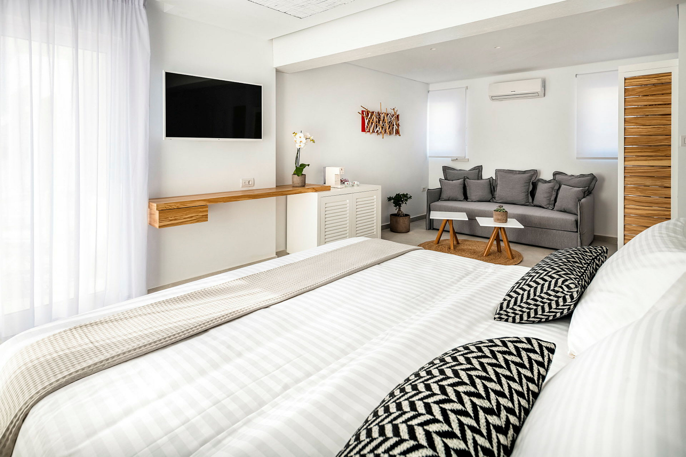 Ett ljus, modernt hotellrum med säng, soffa och TV. (AI-genererad text)