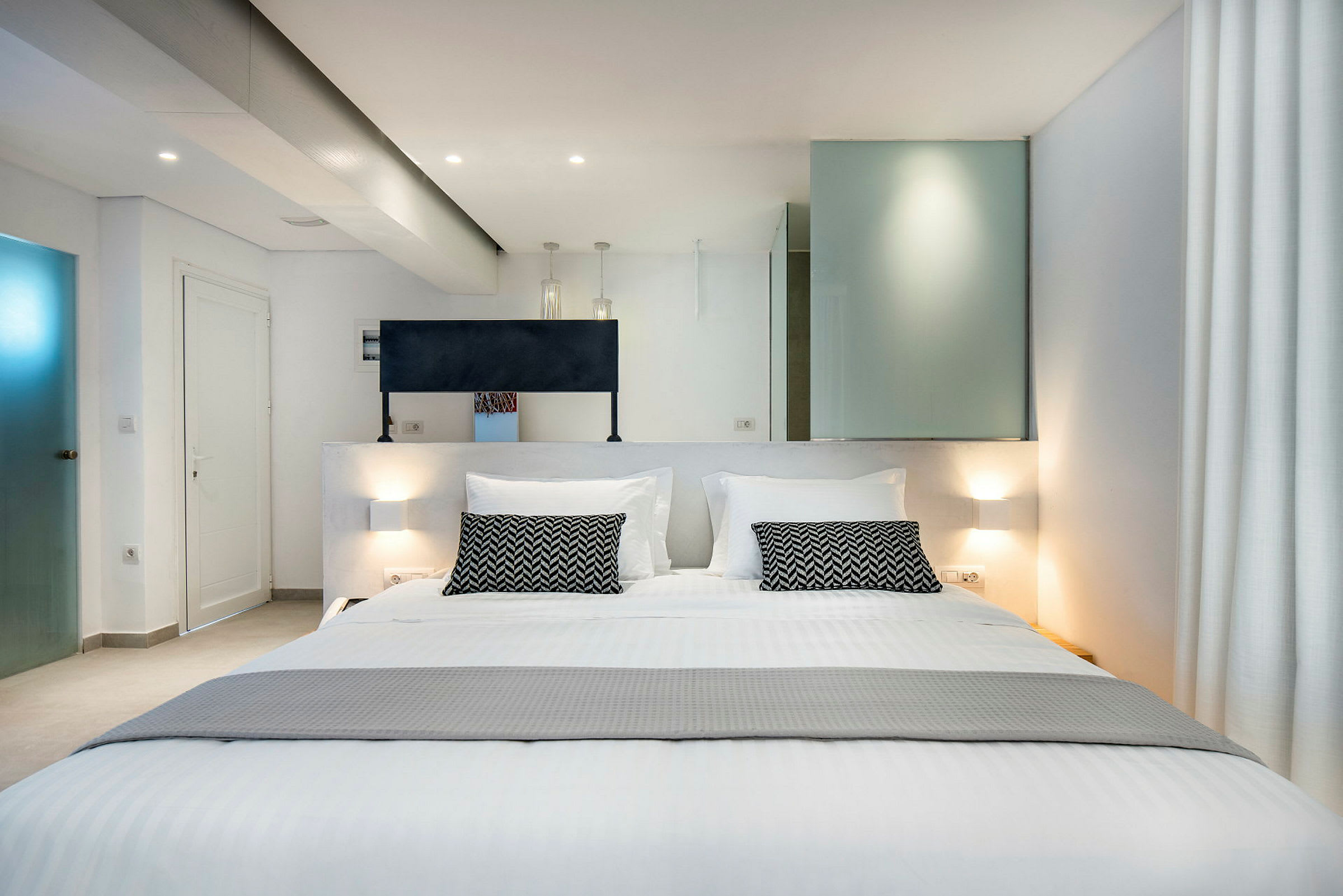 Ett modernt hotellrum med en stor dubbelsäng och stilrena inredningsdetaljer. (AI-genererad text)