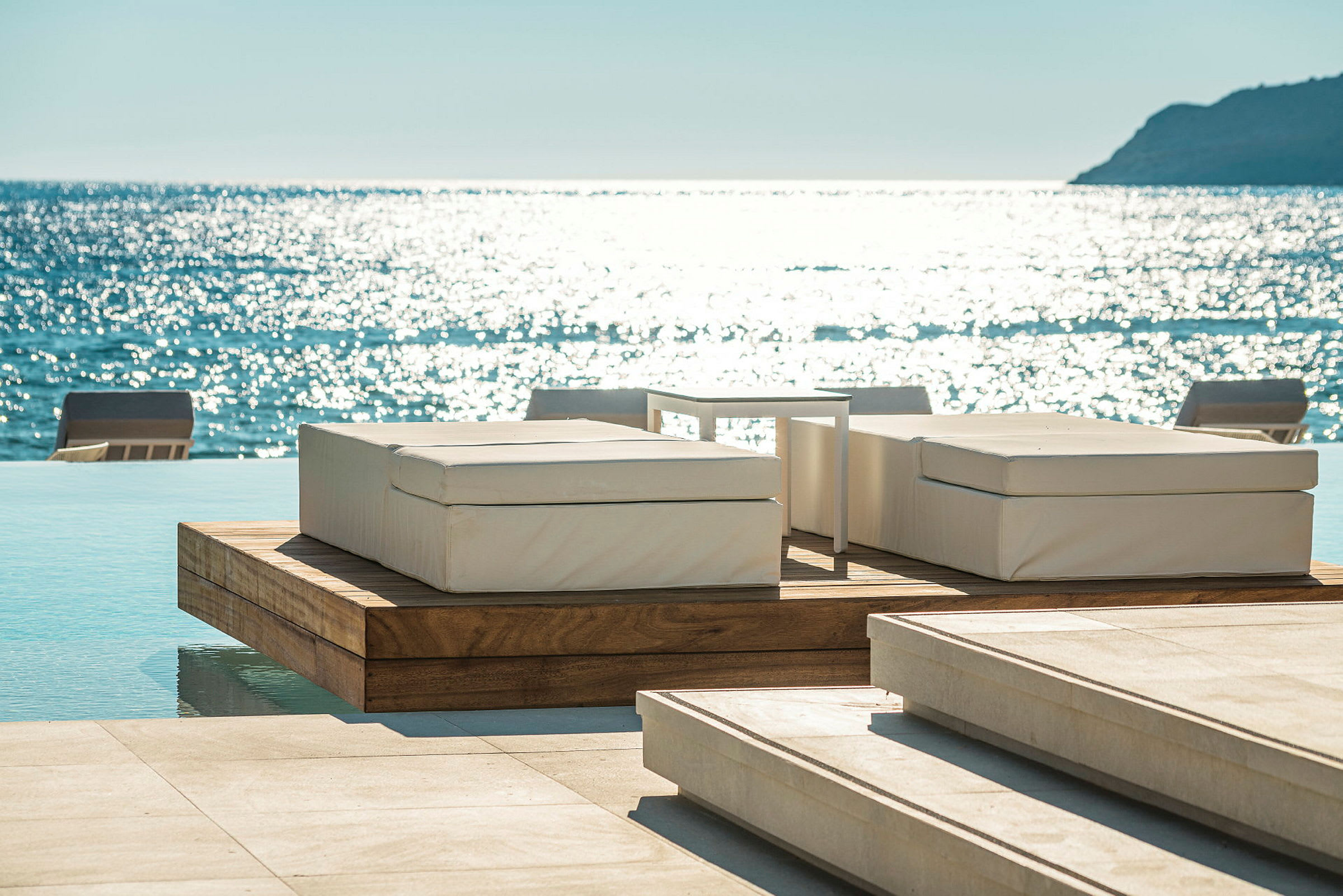 Solstolar vid en infinitypool med havet i bakgrunden. (AI-genererad text)