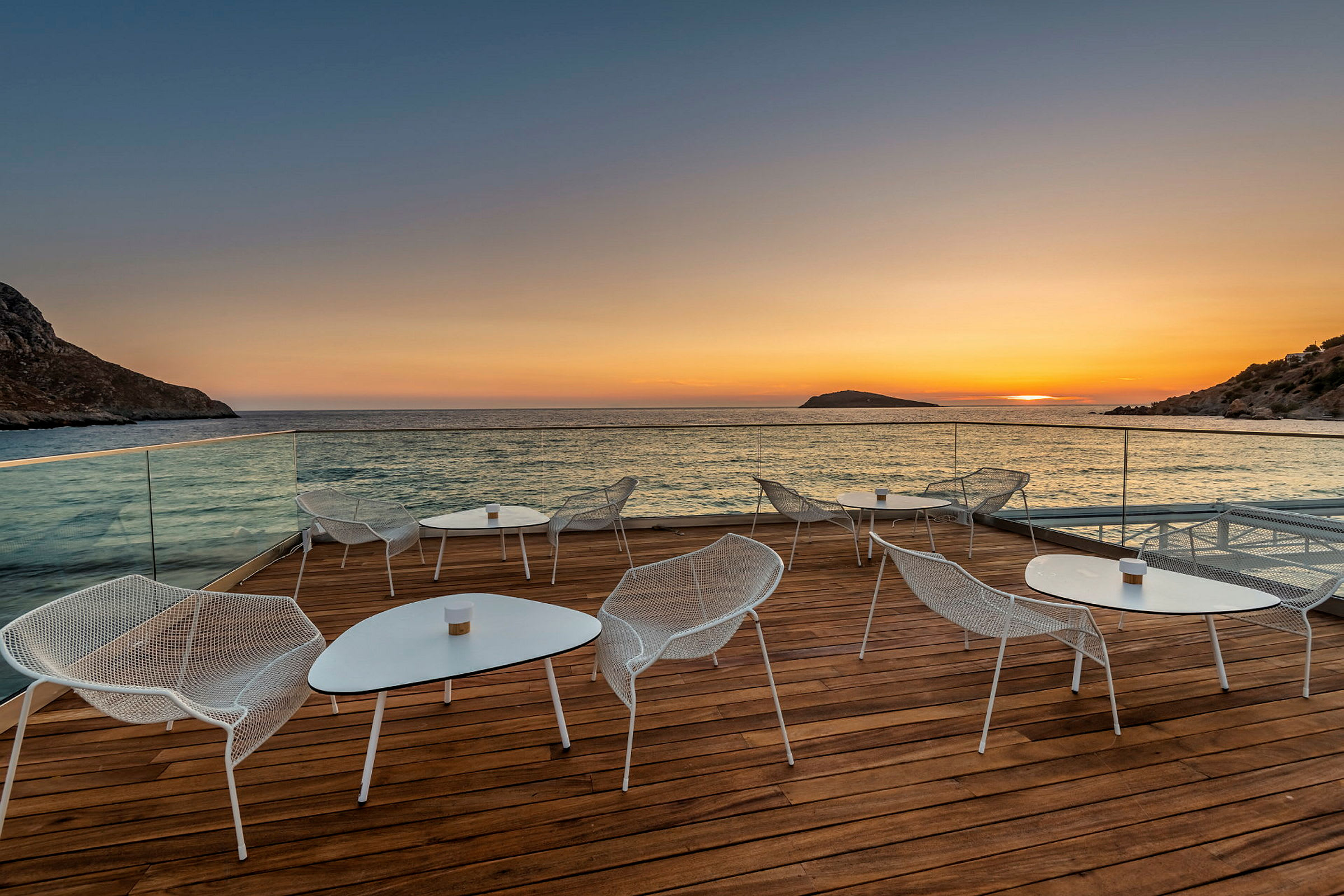 En terrass med sittmöbler vid havet vid solnedgång. (AI-genererad text)