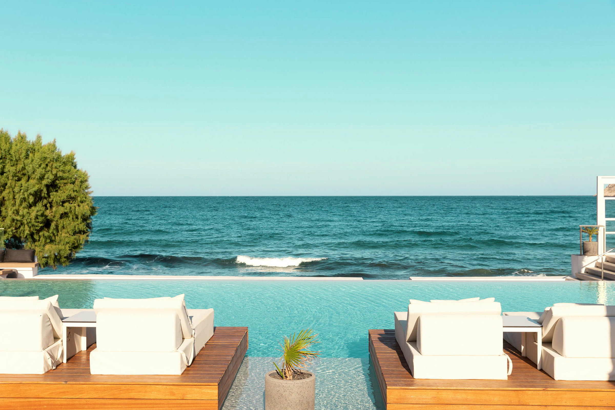Solstolar vid en pool med havet i bakgrunden. (AI-genererad text)
