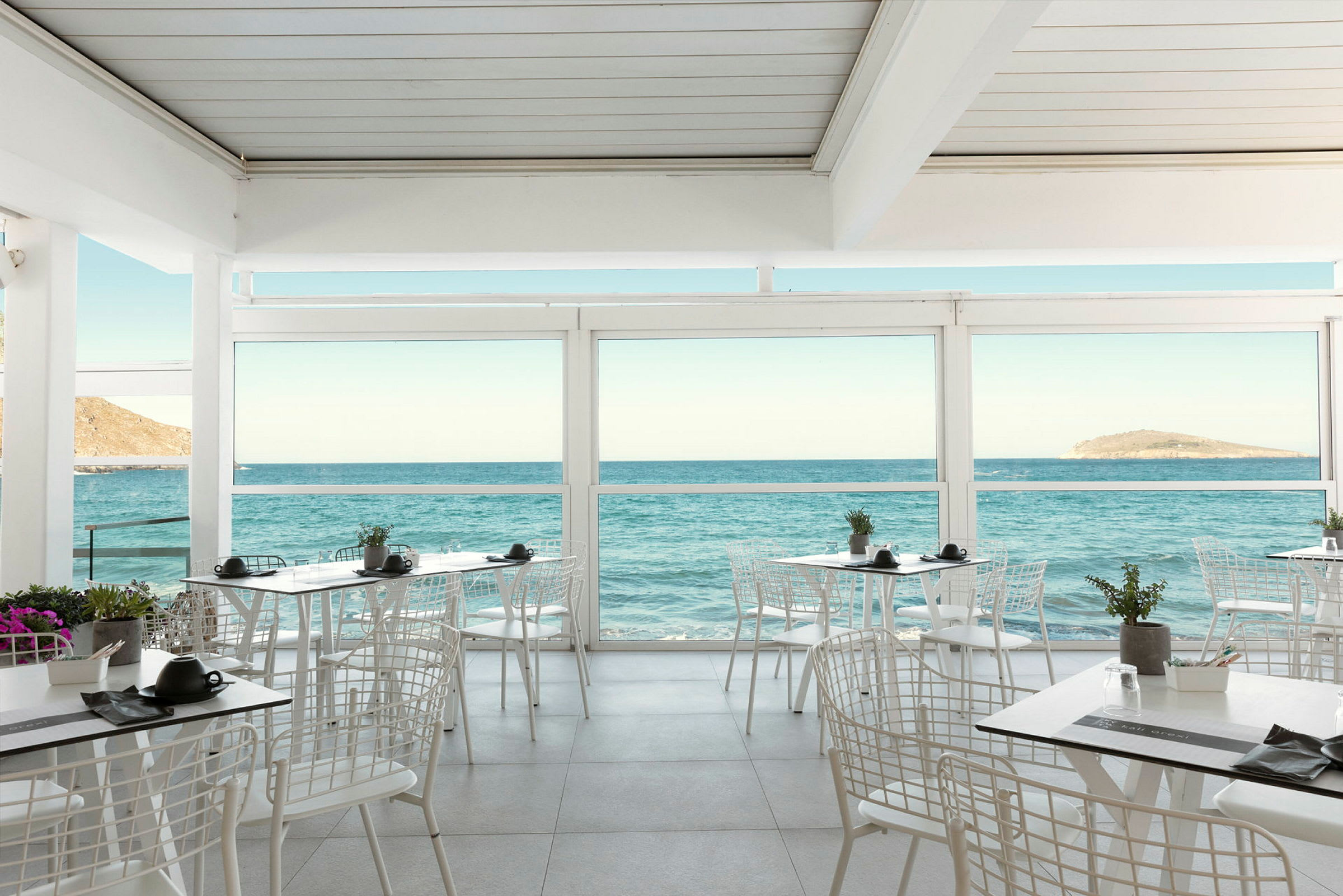 Restaurang med utsikt över havet genom stora fönster. (AI-genererad text)