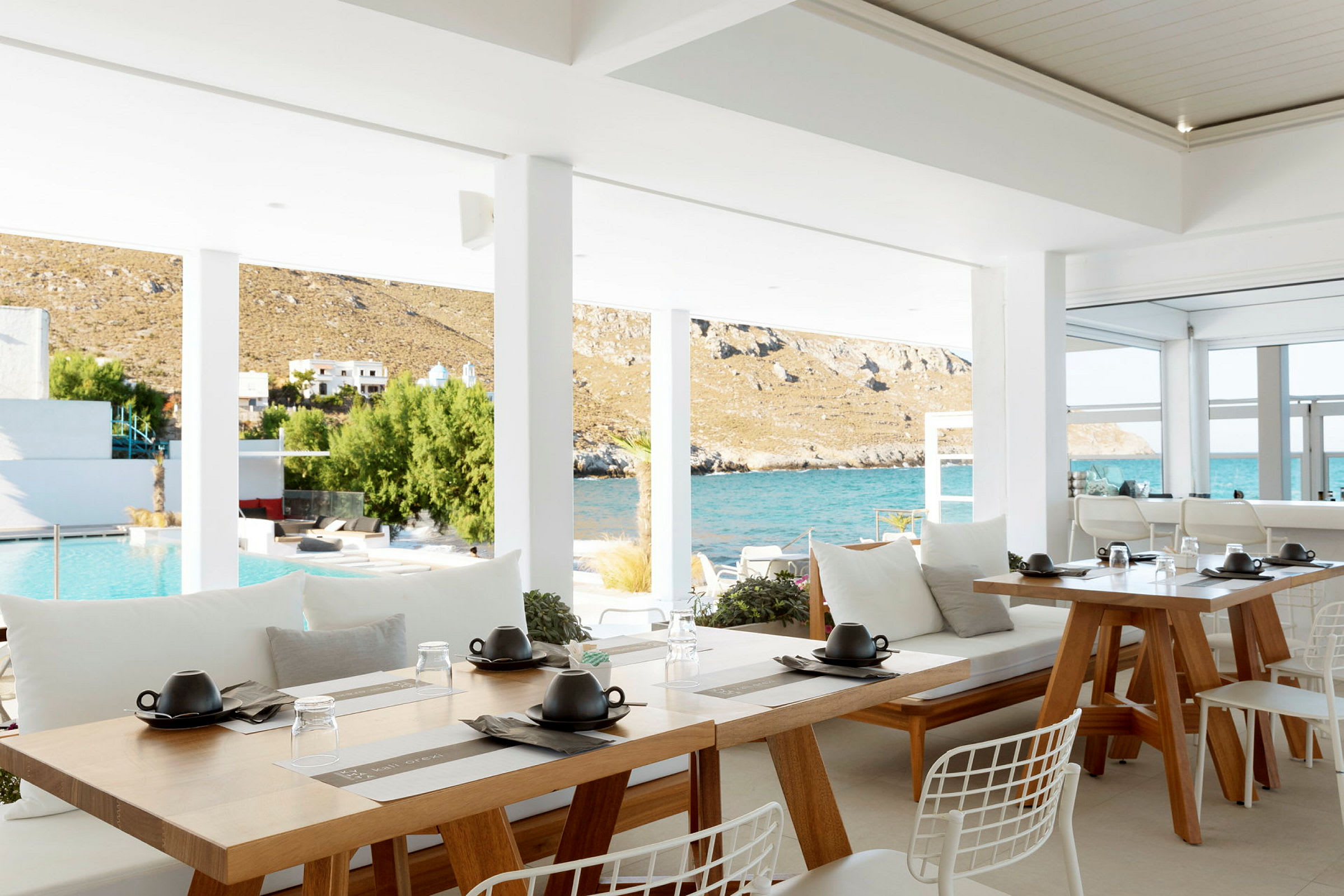 En öppen restaurang med utsikt över en pool och havet bakom. (AI-genererad text)