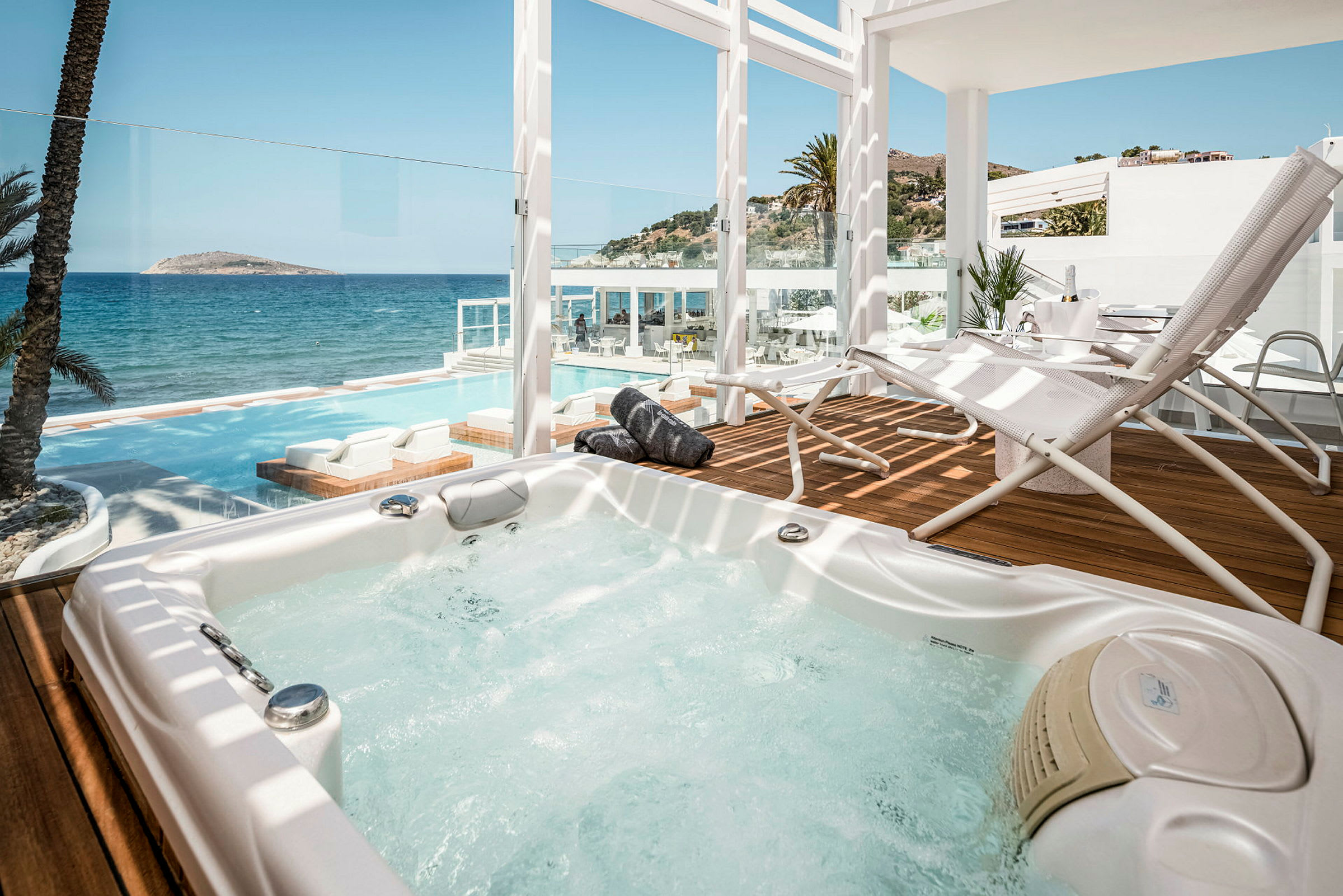 Jacuzzi på en terrass med utsikt över havet och en pool. (AI-genererad text)