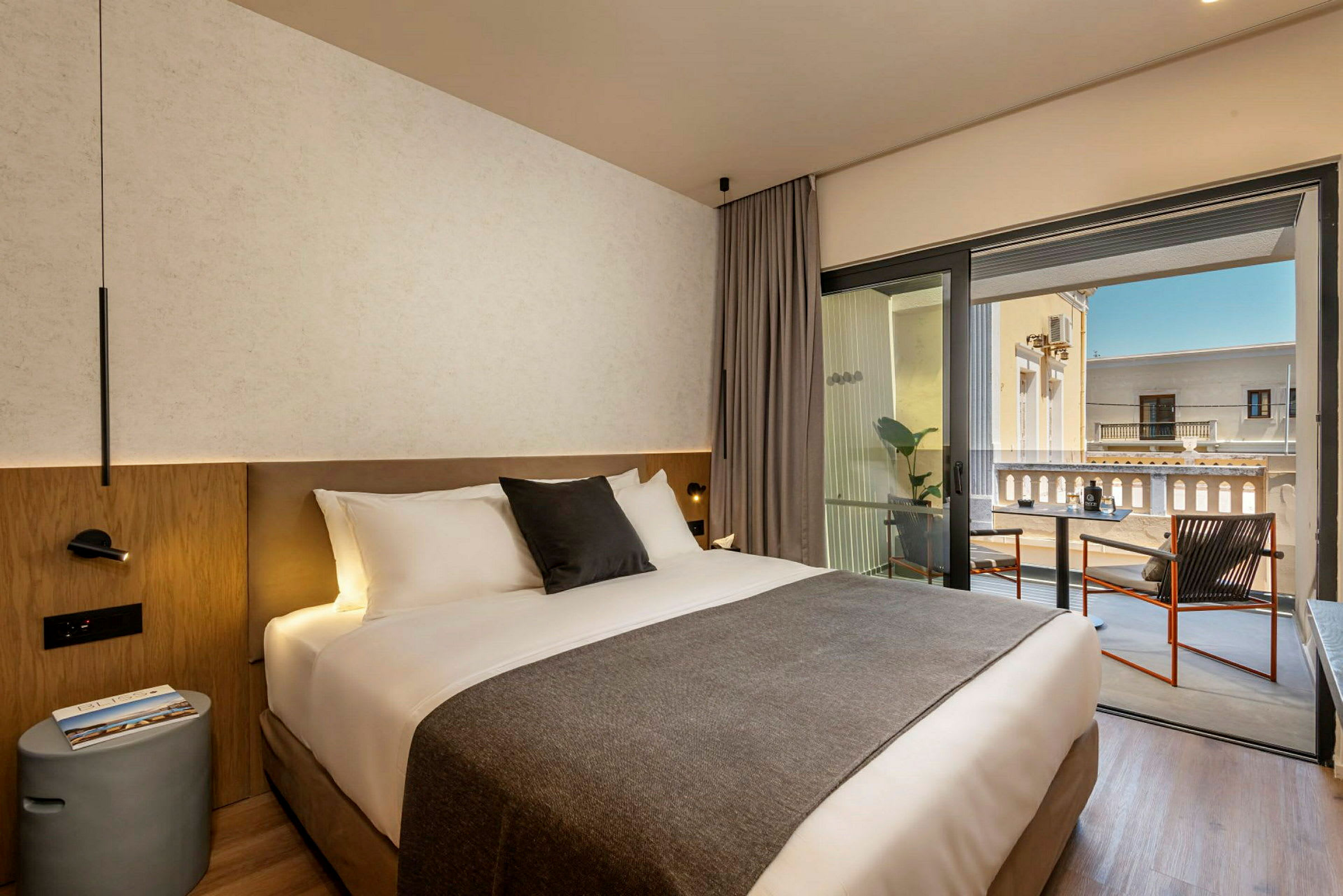 En hotellrum med en dubbelsäng och en balkong med sittplatser. (AI-genererad text)