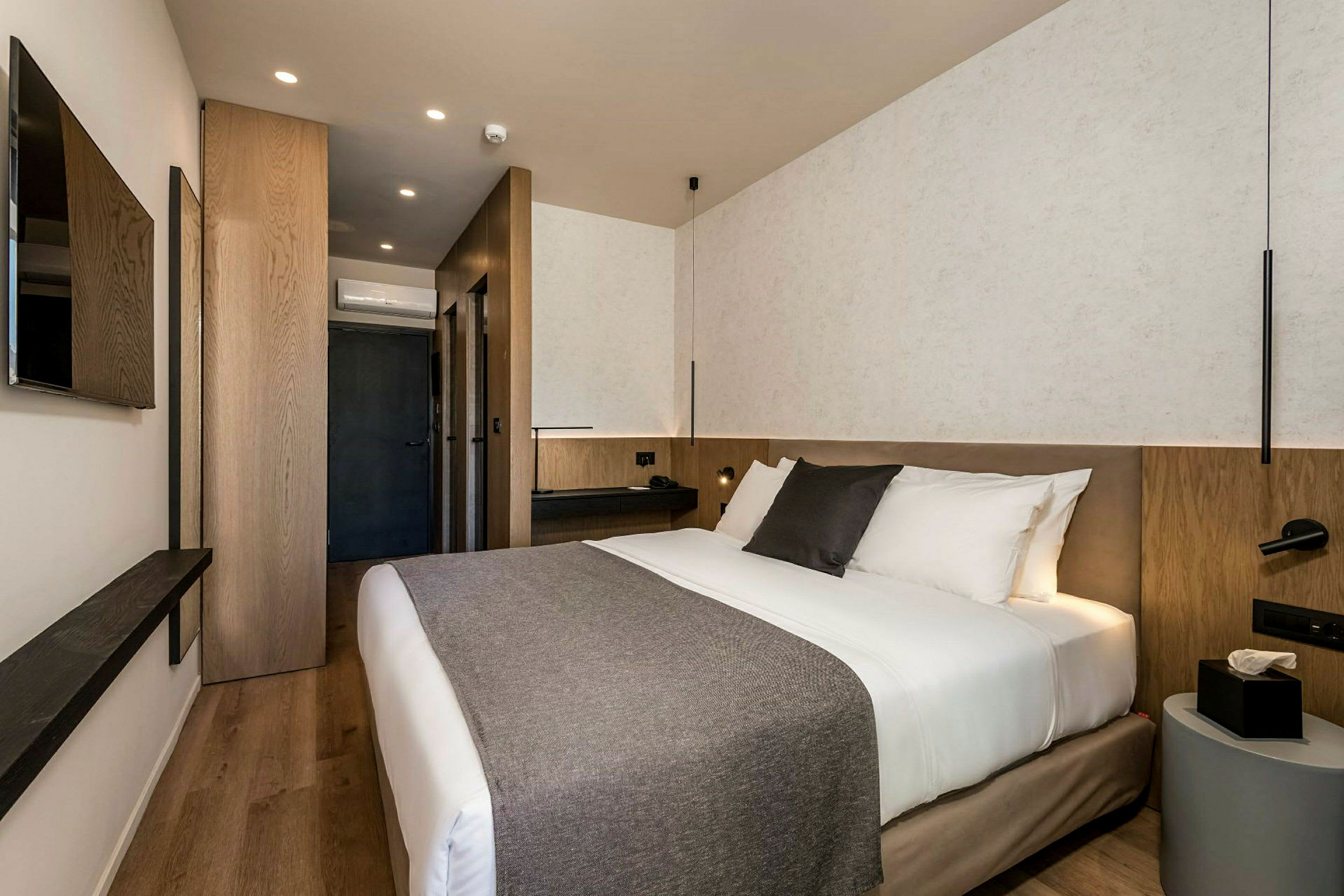 Modernt hotellrum med dubbelsäng, sängbord och väggmonterad TV. (AI-genererad text)