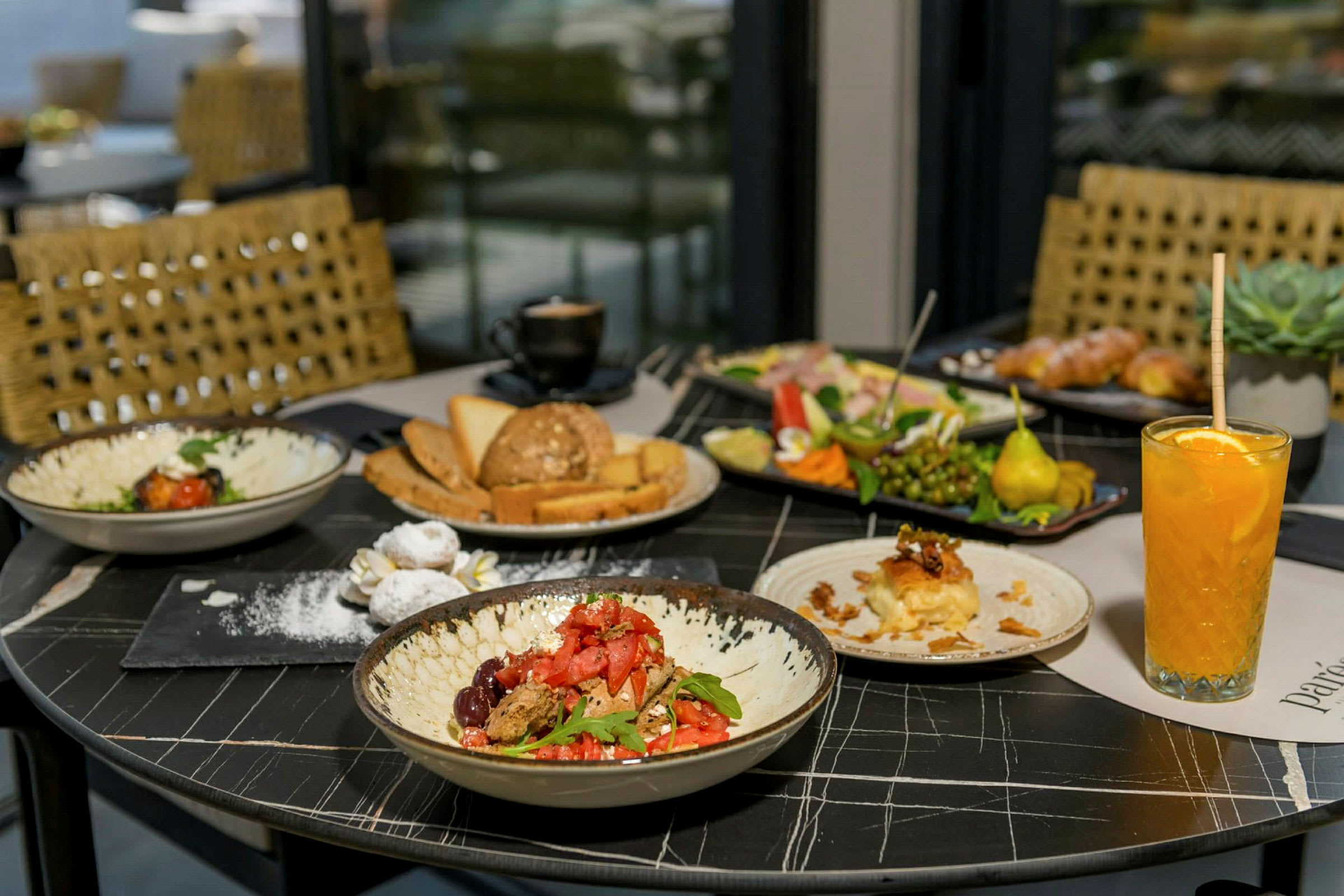 Ett bord med olika maträtter, inklusive sallader, bakverk, frukt och en orange dryck. (AI-genererad text)