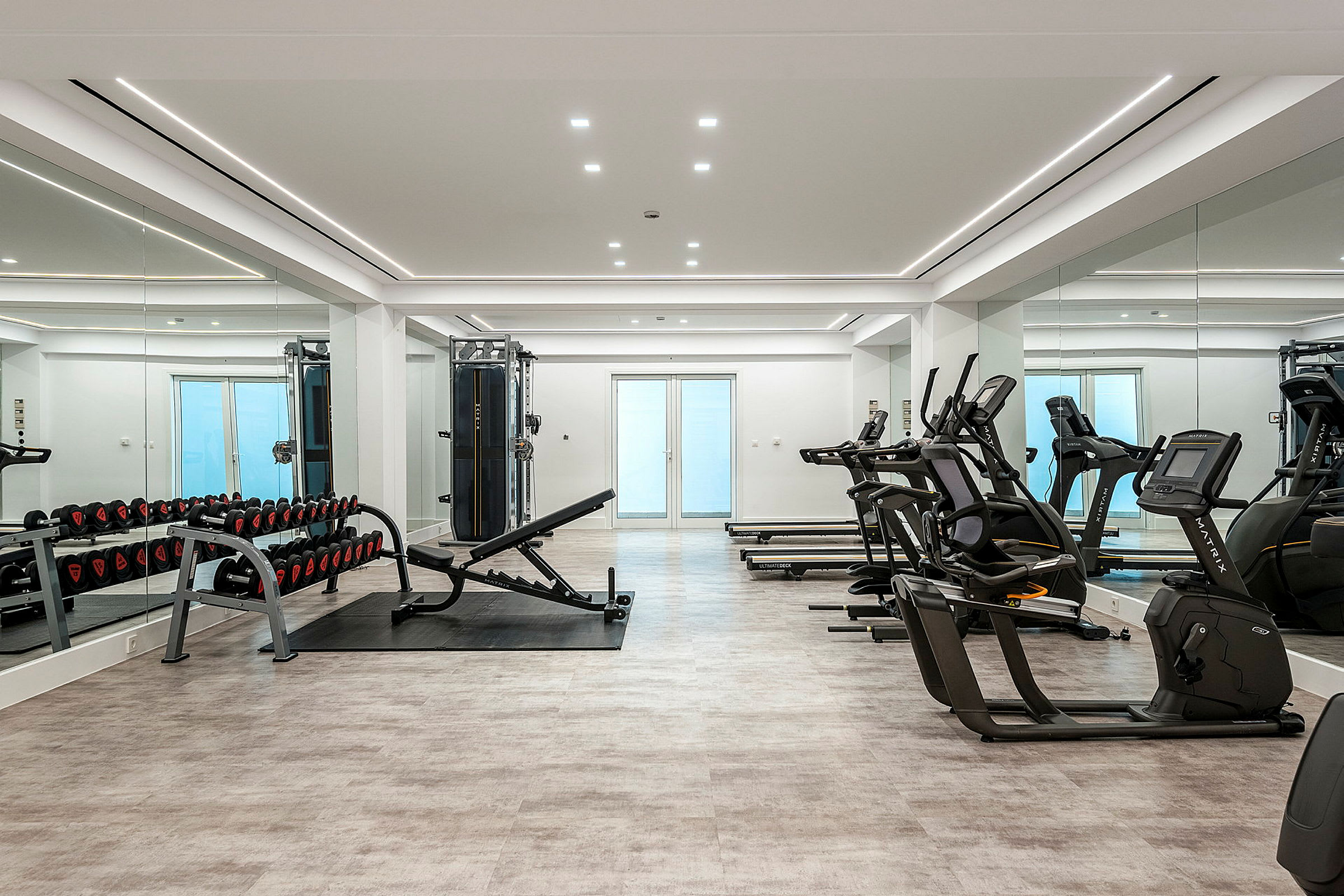 Ett modernt gym med träningsmaskiner, vikter och speglar. (AI-genererad text)