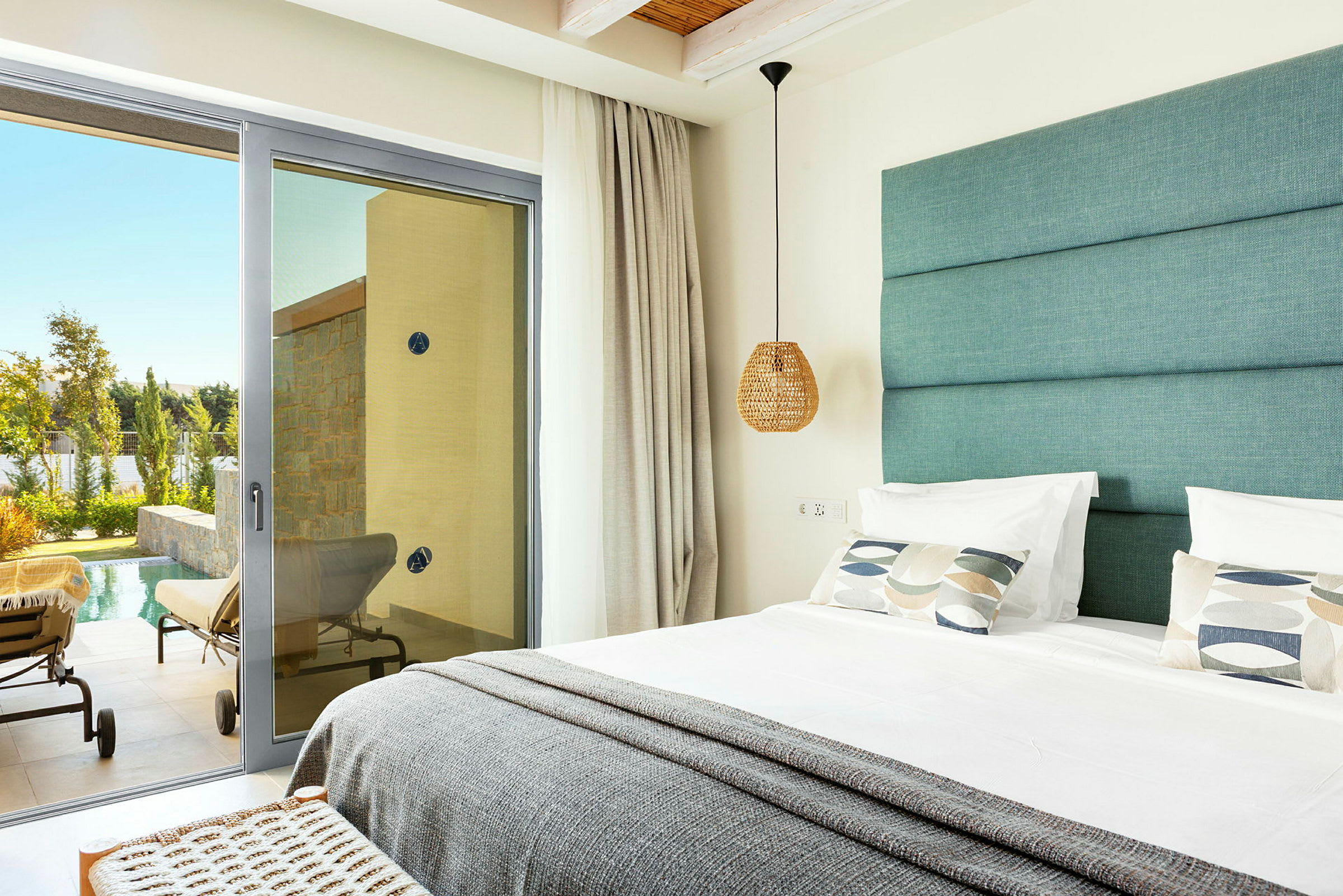 Visar en modern hotellrum med en dubbelsäng och en glasdörr som leder till en terrass med solstolar vid en pool. (AI-genererad text)