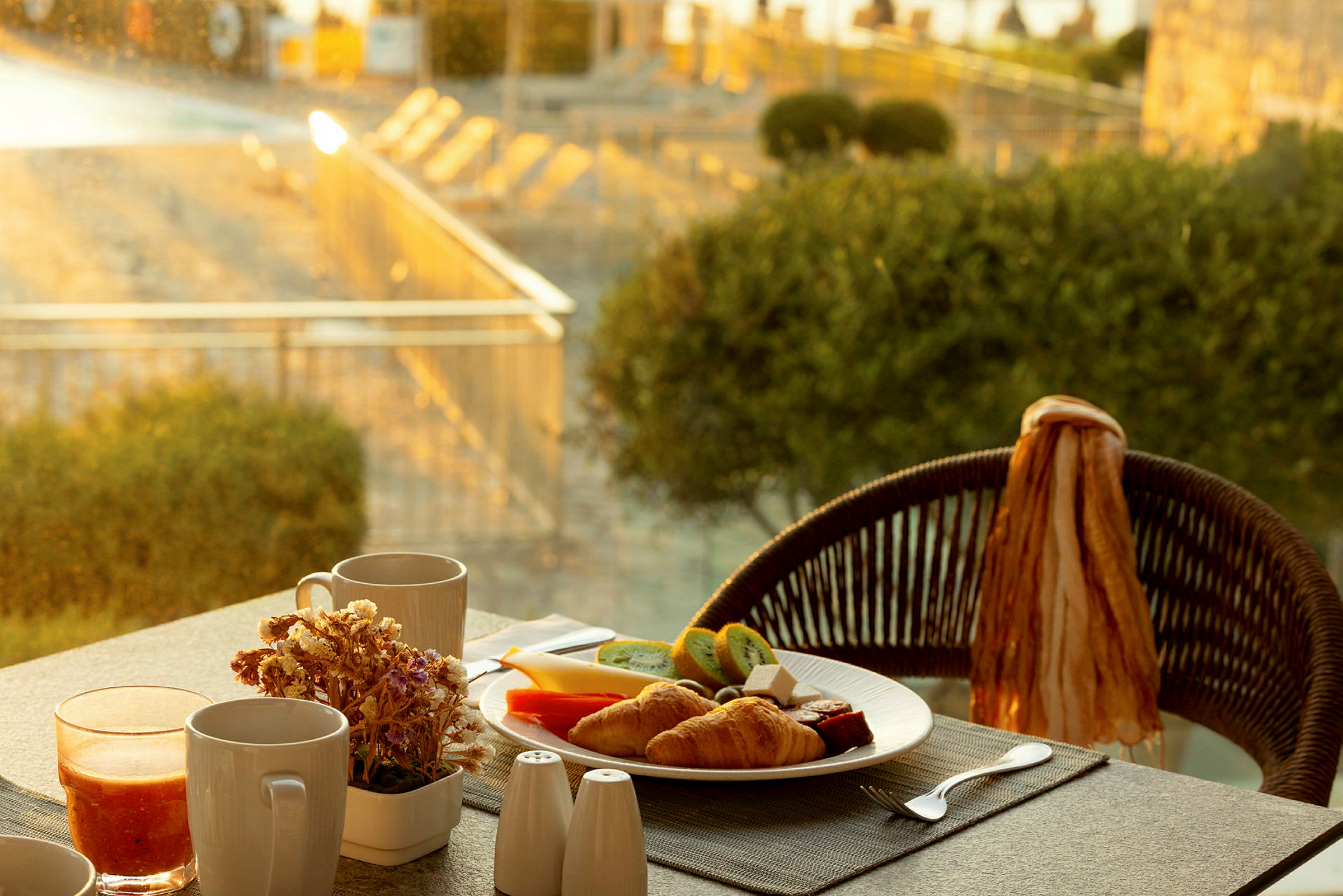 Tallrik med frukostmat och drycker på ett bord med utsikt över en solig trädgård. (AI-genererad text)