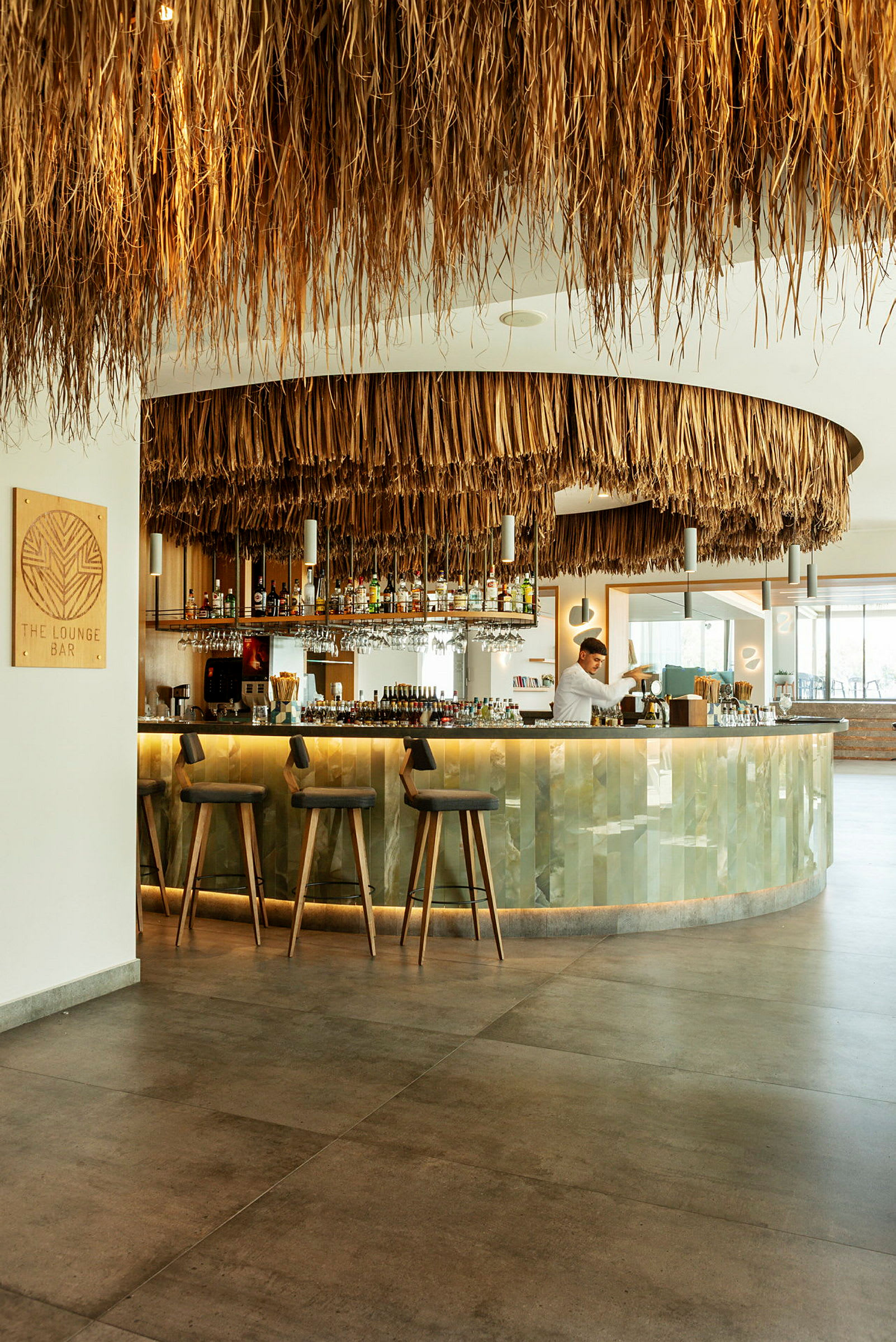 En modern loungebar med ett tak dekorerat med naturliga material och en välutrustad bardisk. (AI-genererad text)