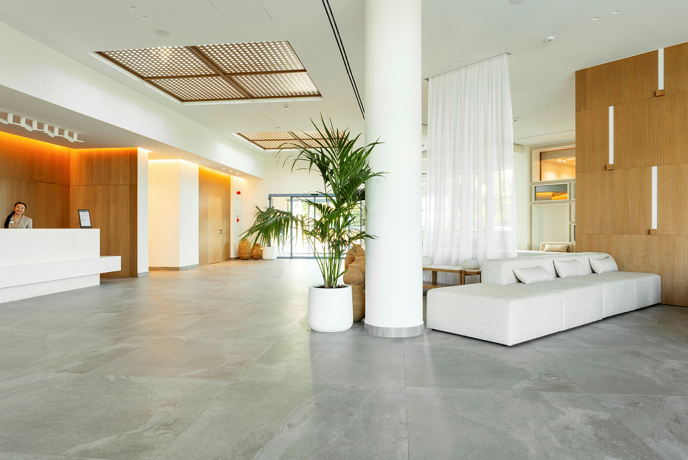 Inne i en modern hotellobby med en reception, soffor och växter. (AI-genererad text)