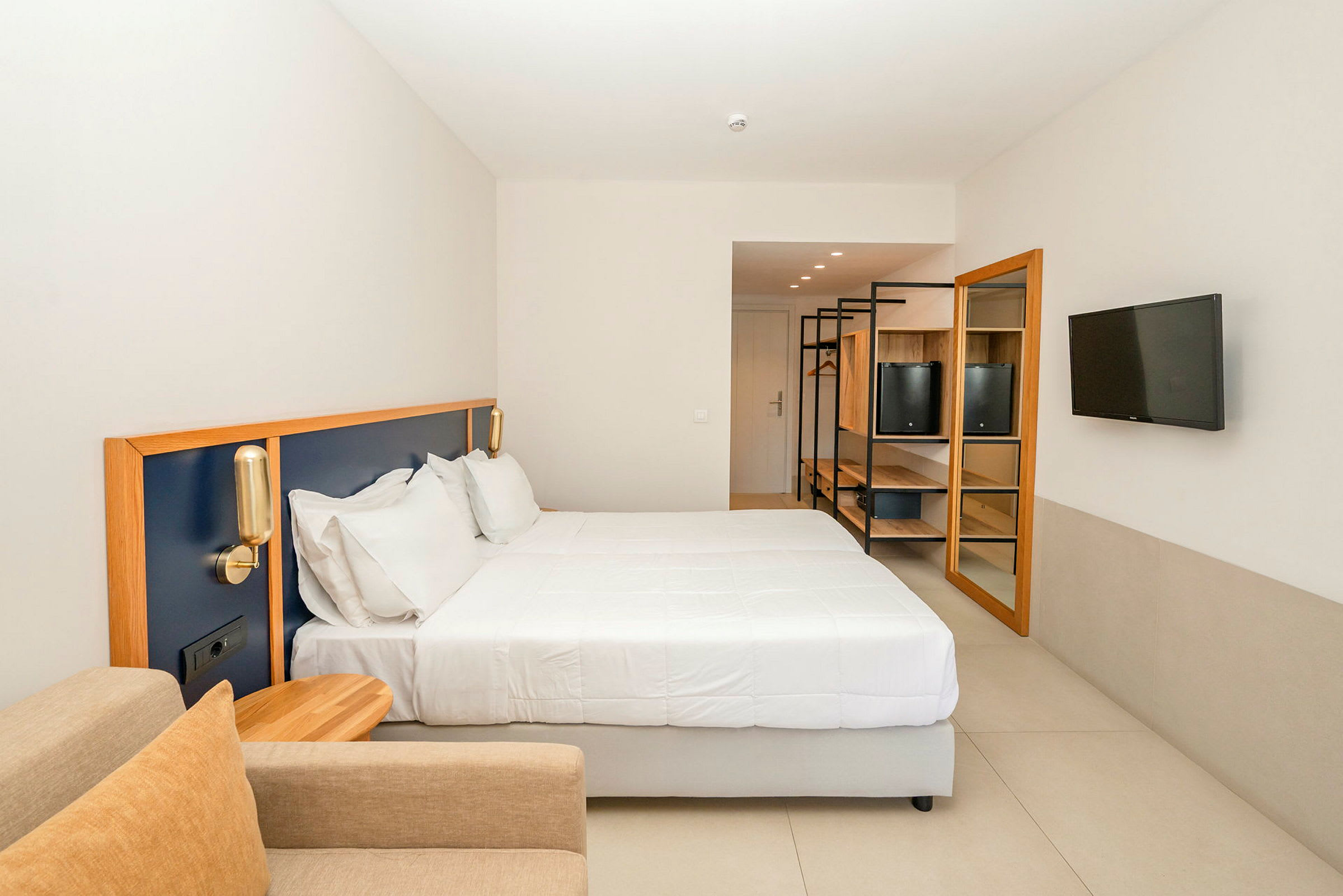 Ett hotellrum med en stor säng, sittmöbler och en tv på väggen. (AI-genererad text)