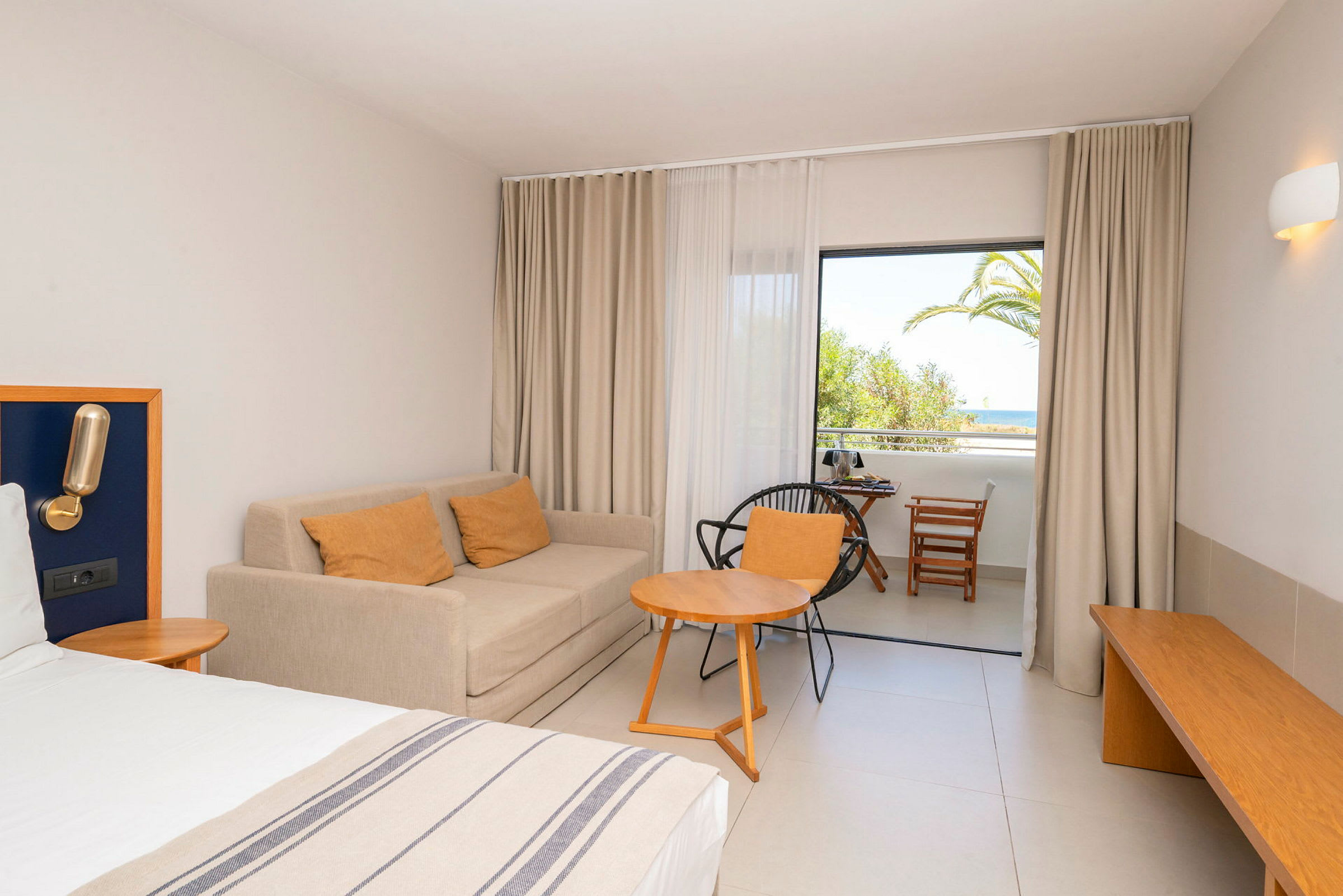 Bild av hotellrum med en bädd, soffa och möbler samt utsikt mot balkong. (AI-genererad text)