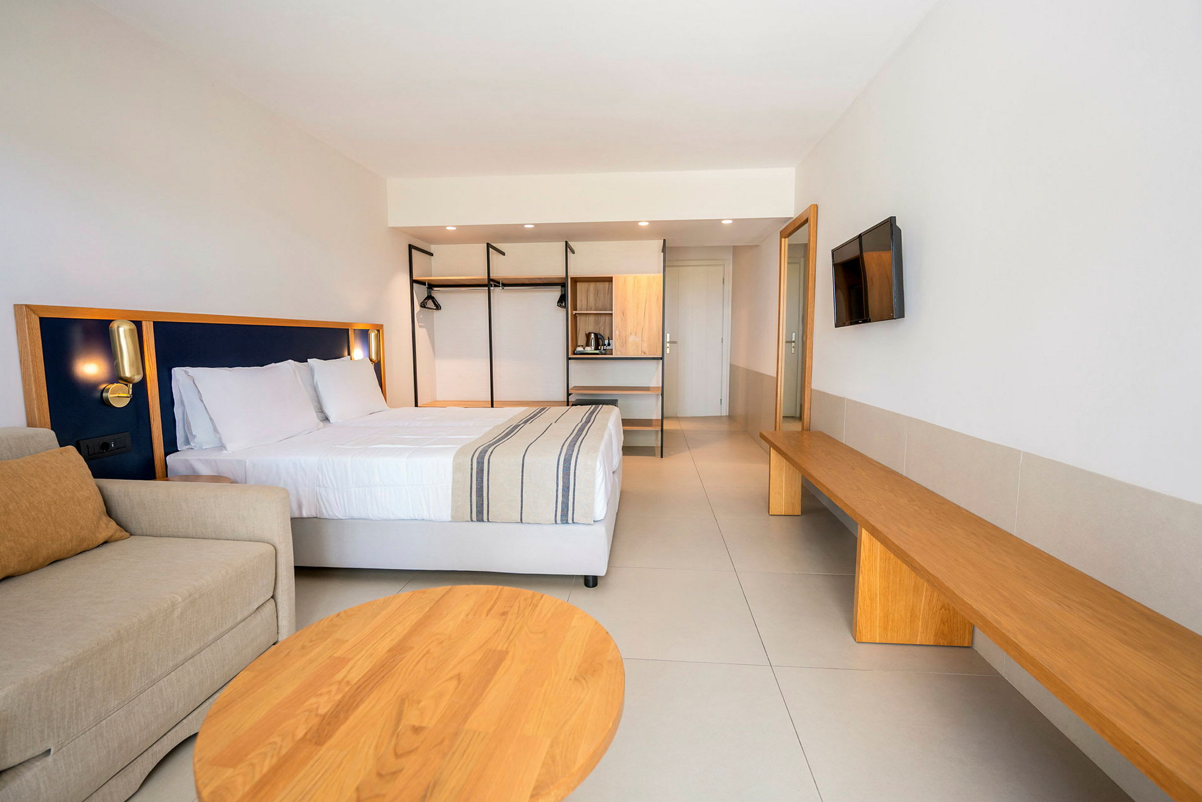 Ett modernt hotellrum med en dubbelsäng, soffa, och träinredning. (AI-genererad text)