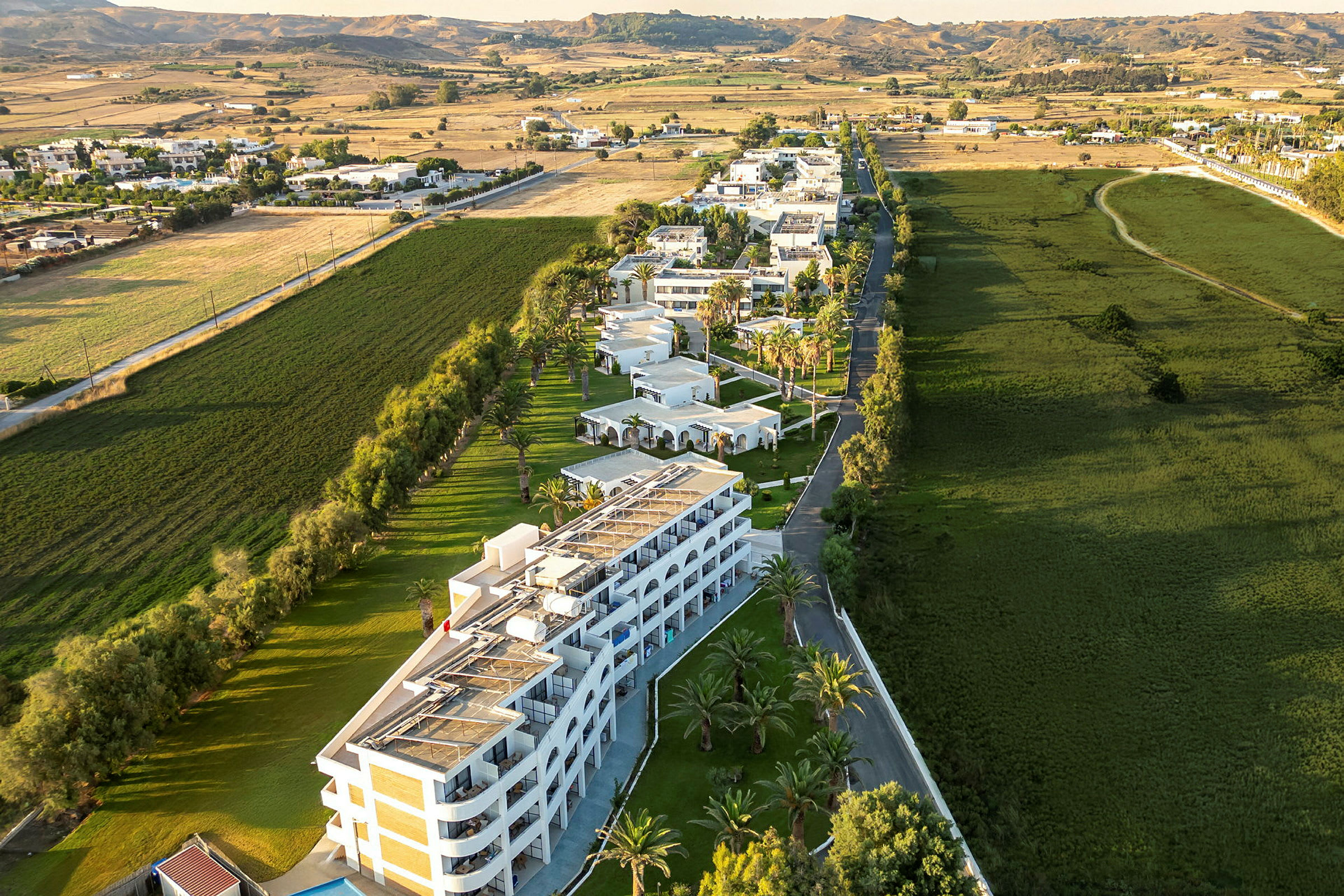 Flygfoto av ett hotellkomplex omgivet av grönområden och landskap. (AI-genererad text)