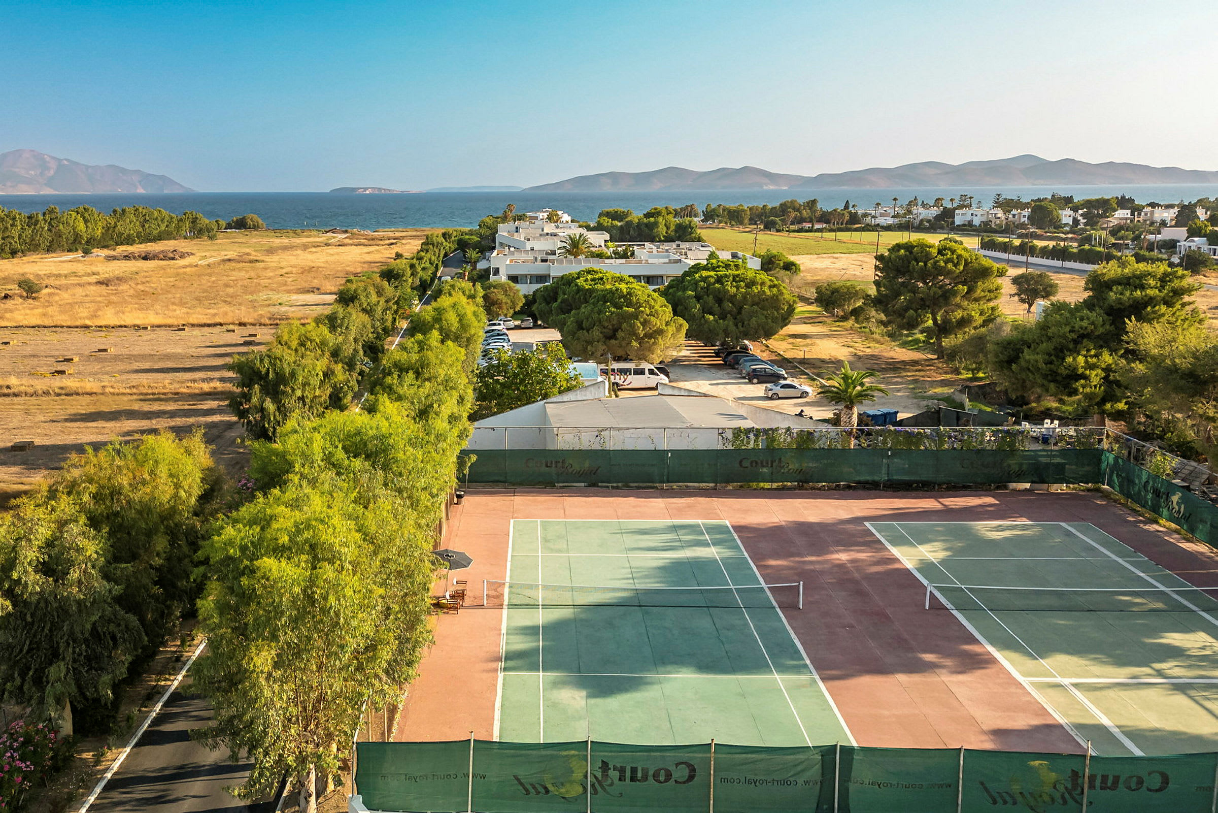 Tennisbanor med landskap och hav i bakgrunden. (AI-genererad text)