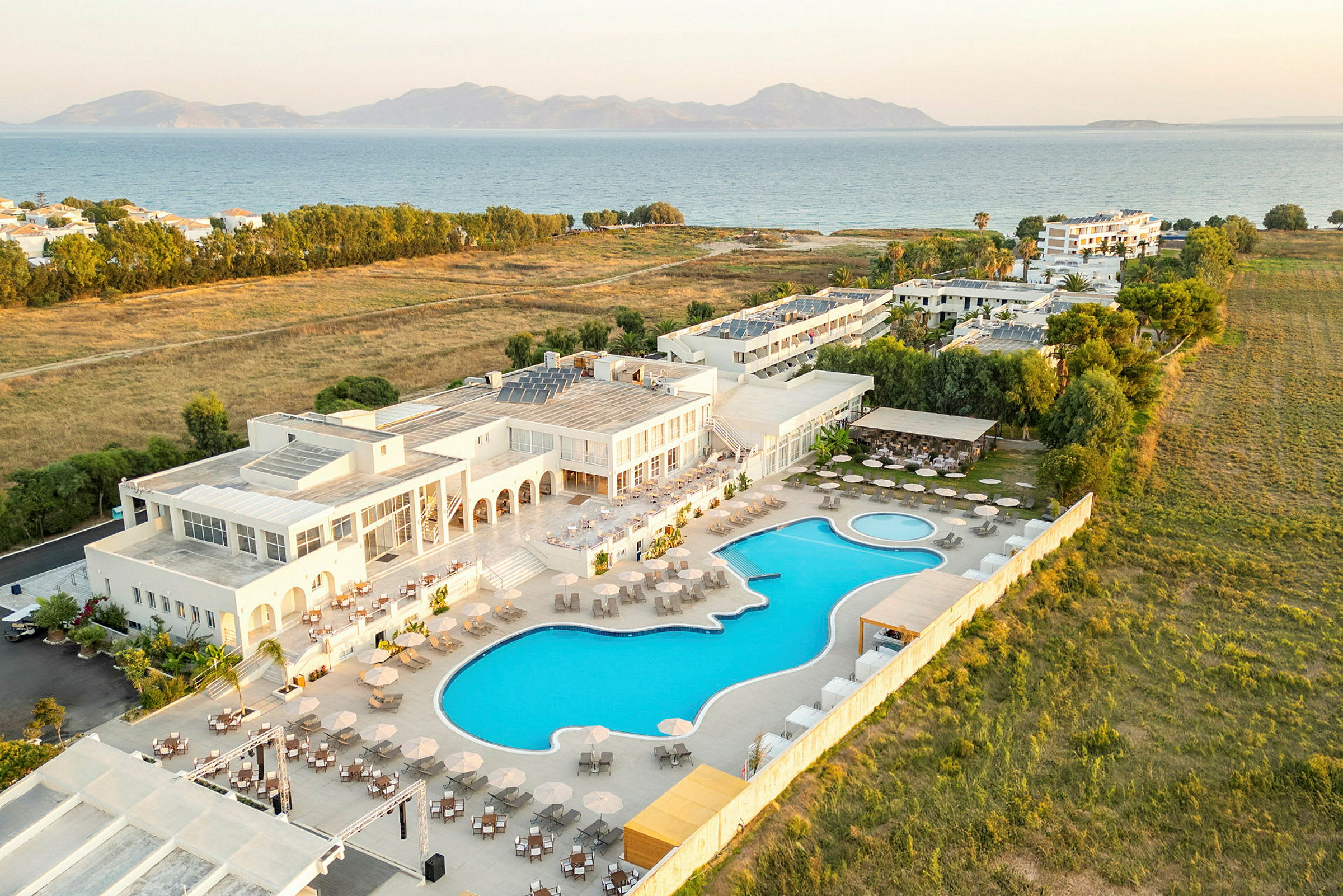 Luftvy av ett hotell med pool och omgivande grönområden. (AI-genererad text)