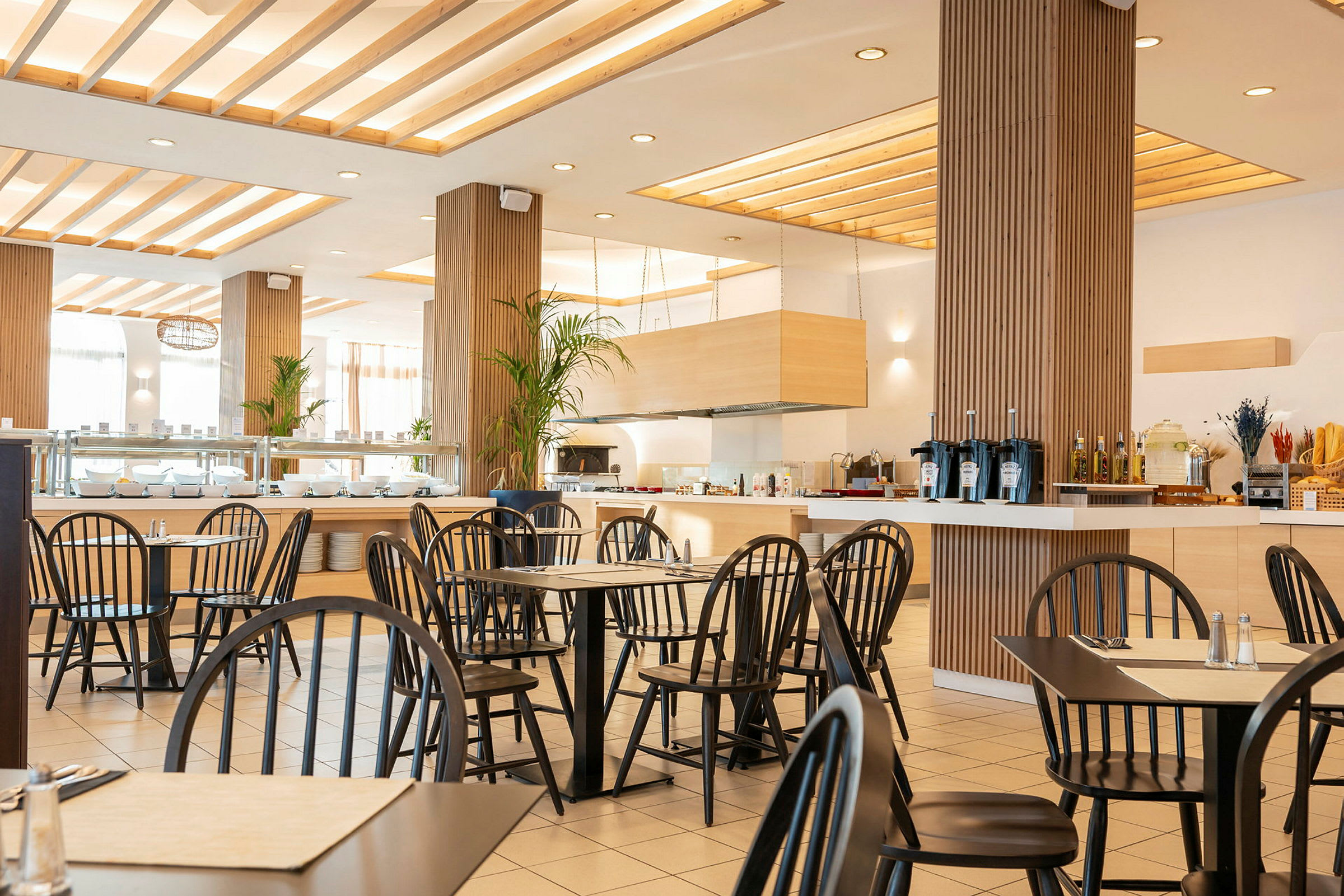 En modern restaurang med svarta stolar och ljus inredning. (AI-genererad text)