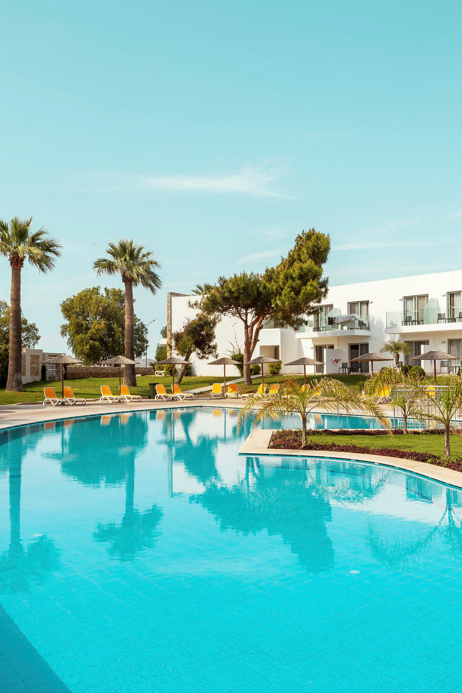 En utomhuspool med solstolar och parasoller vid ett hotell. (AI-genererad text)
