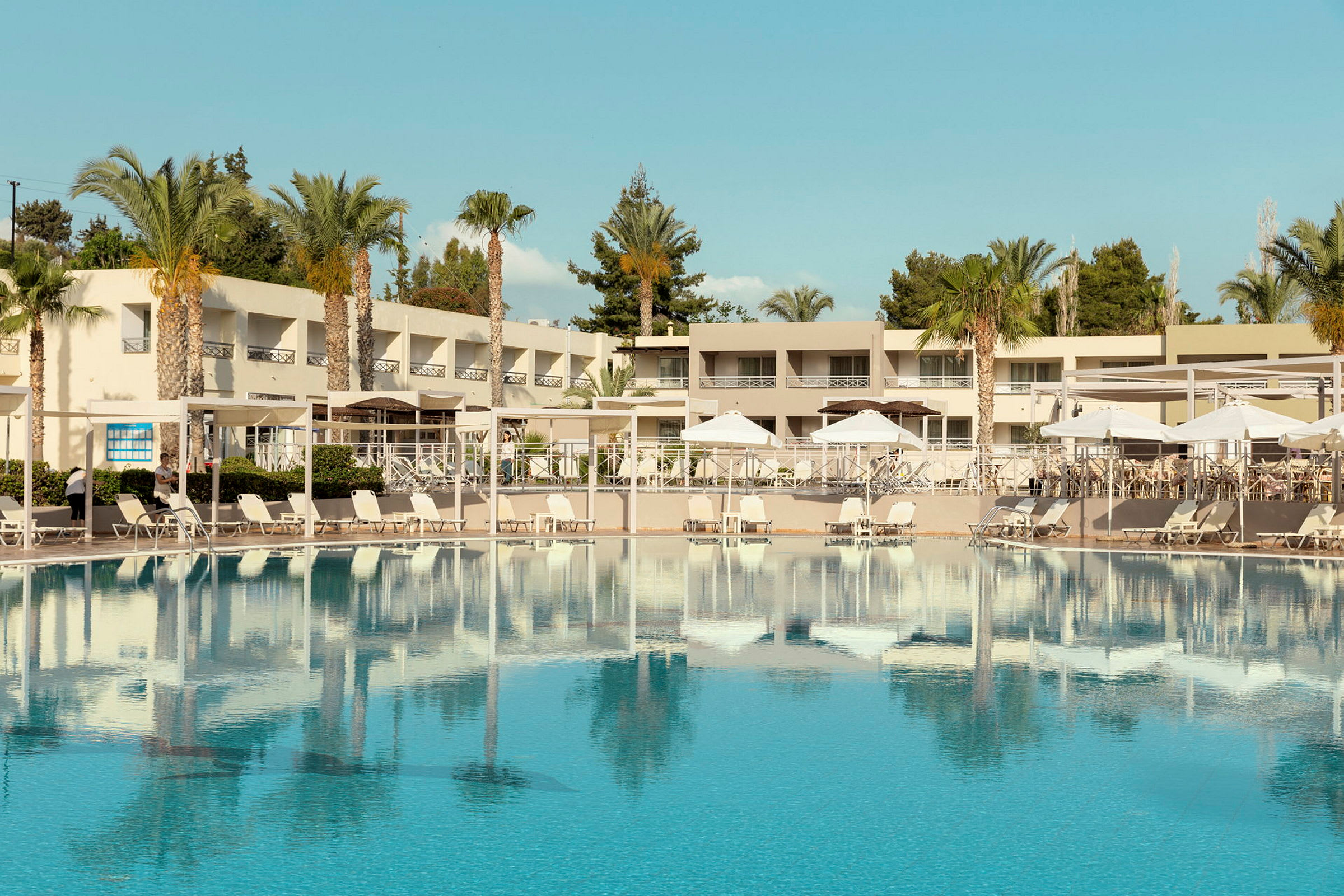 Ett hotellområde med en stor swimmingpool och solstolar. (AI-genererad text)