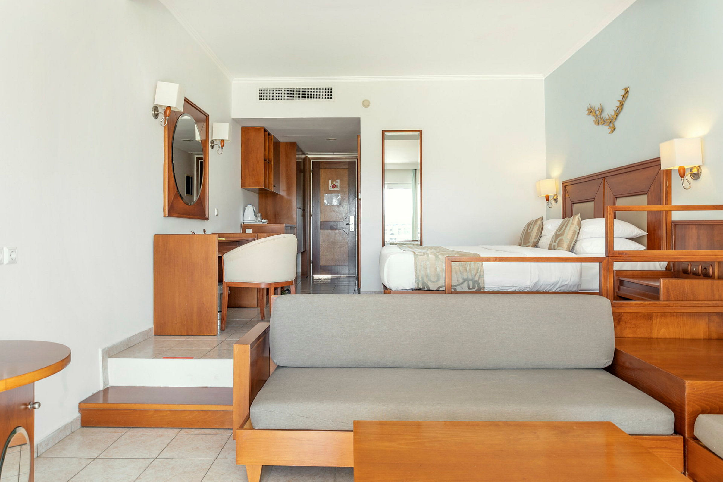 Hotellrum med säng, soffa och skrivbord i träinredning. (AI-genererad text)