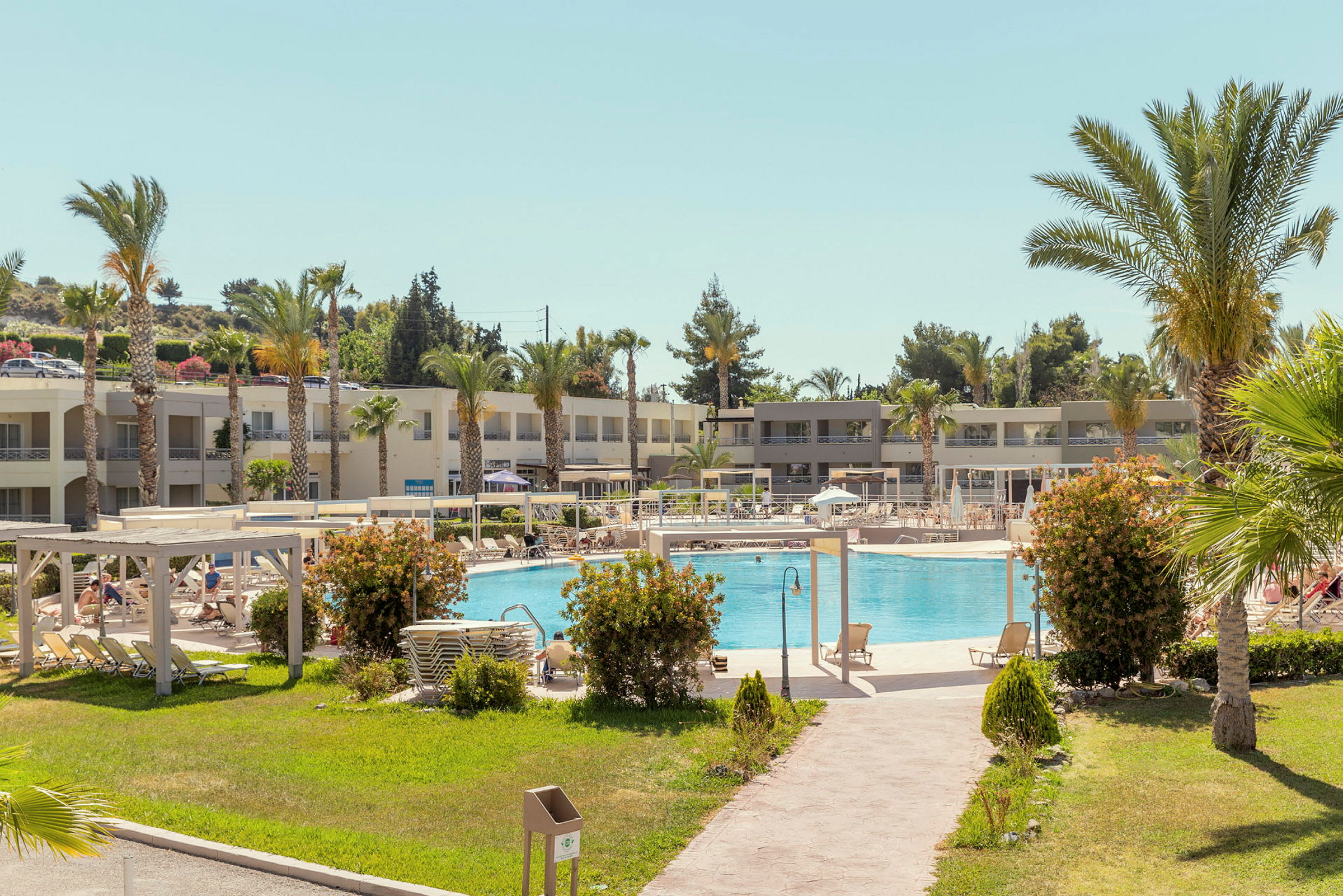 Hotellanläggning med pool, solstolar och grönområde. (AI-genererad text)