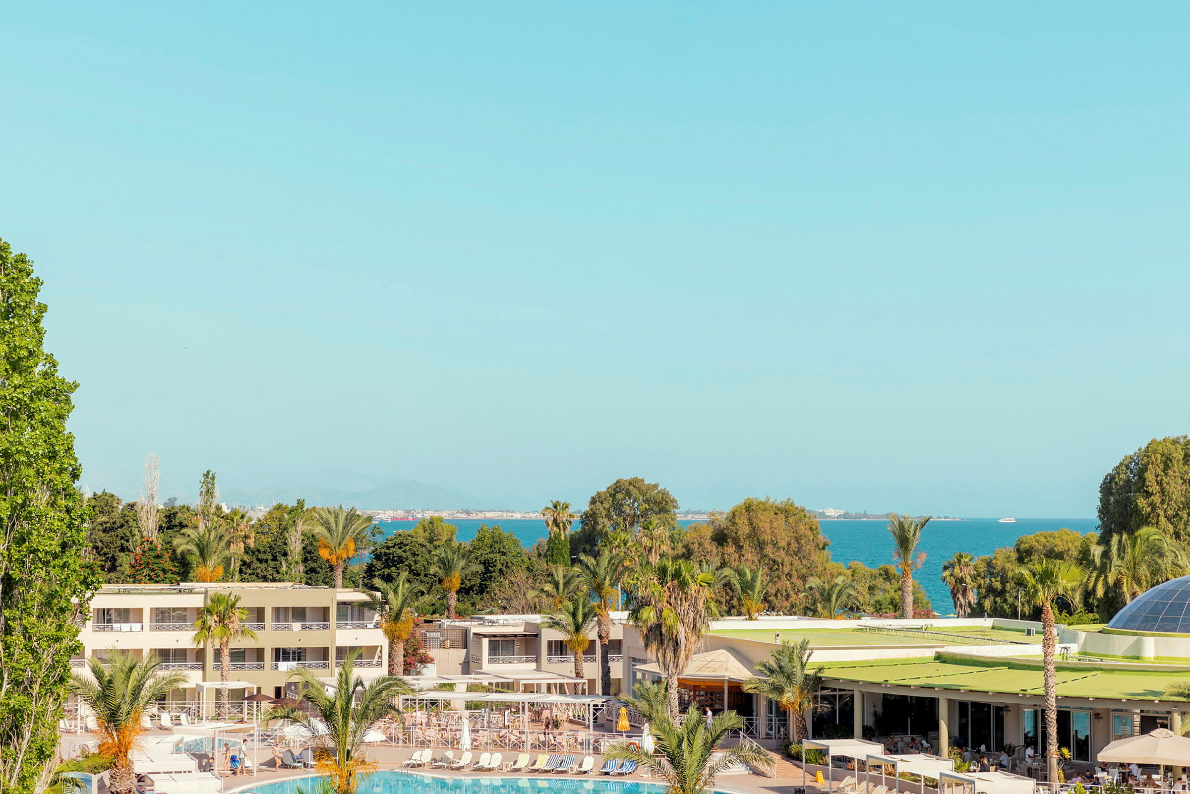 Ett semesterresort vid havet med pool och omgivande palmträd. (AI-genererad text)
