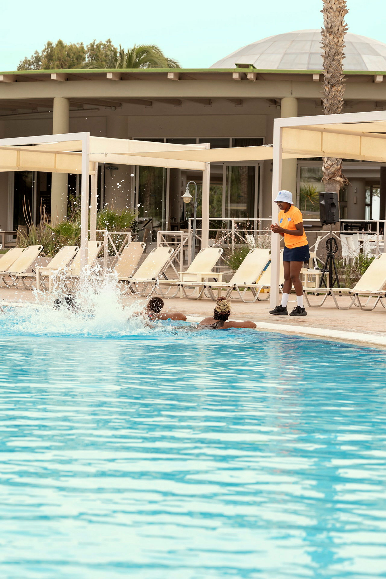 Personer simmar i en pool nära solstolar och ett uterum. (AI-genererad text)