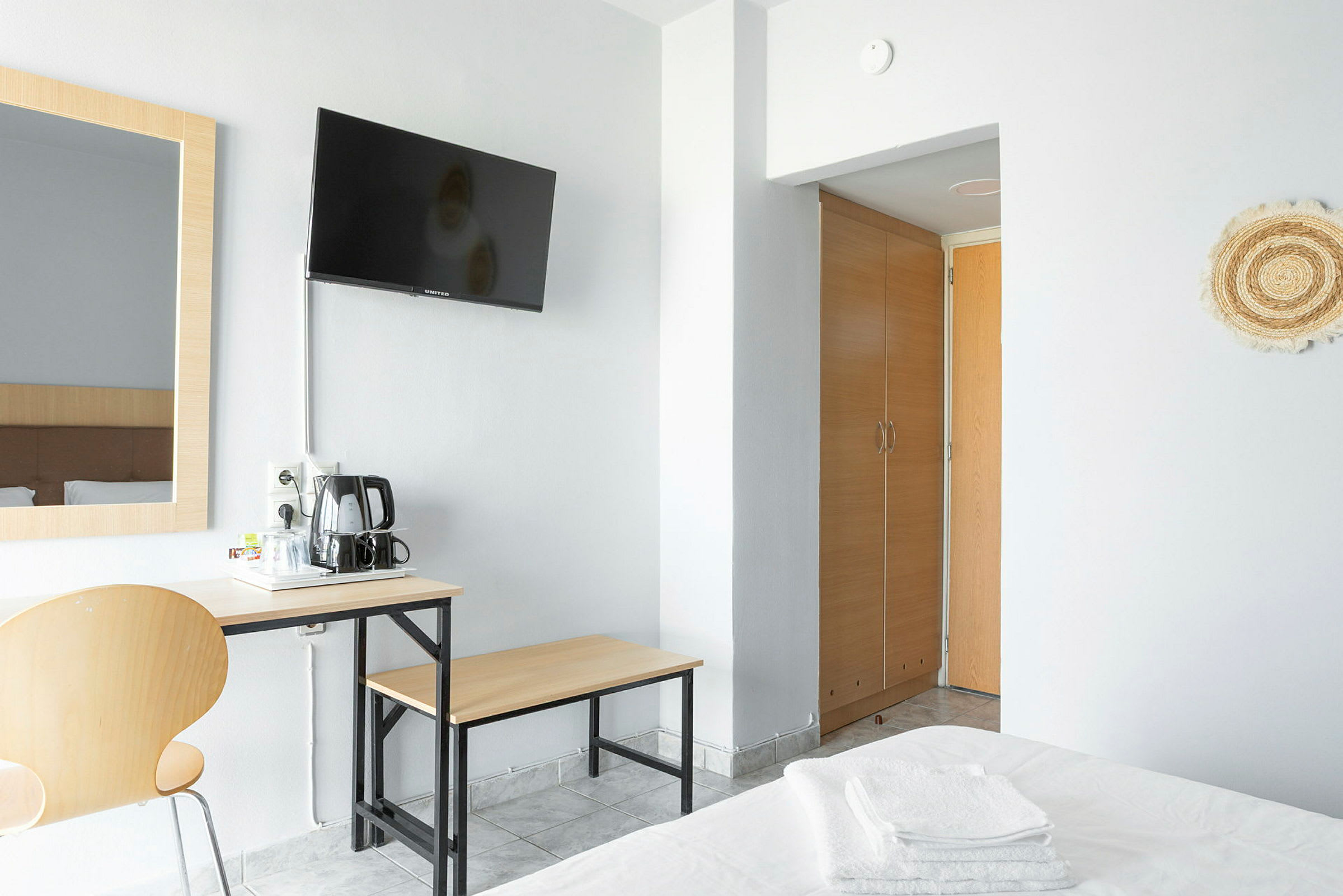 Ett hotellrum med en TV på väggen, ett skrivbord med kaffebryggare, och en garderob. (AI-genererad text)