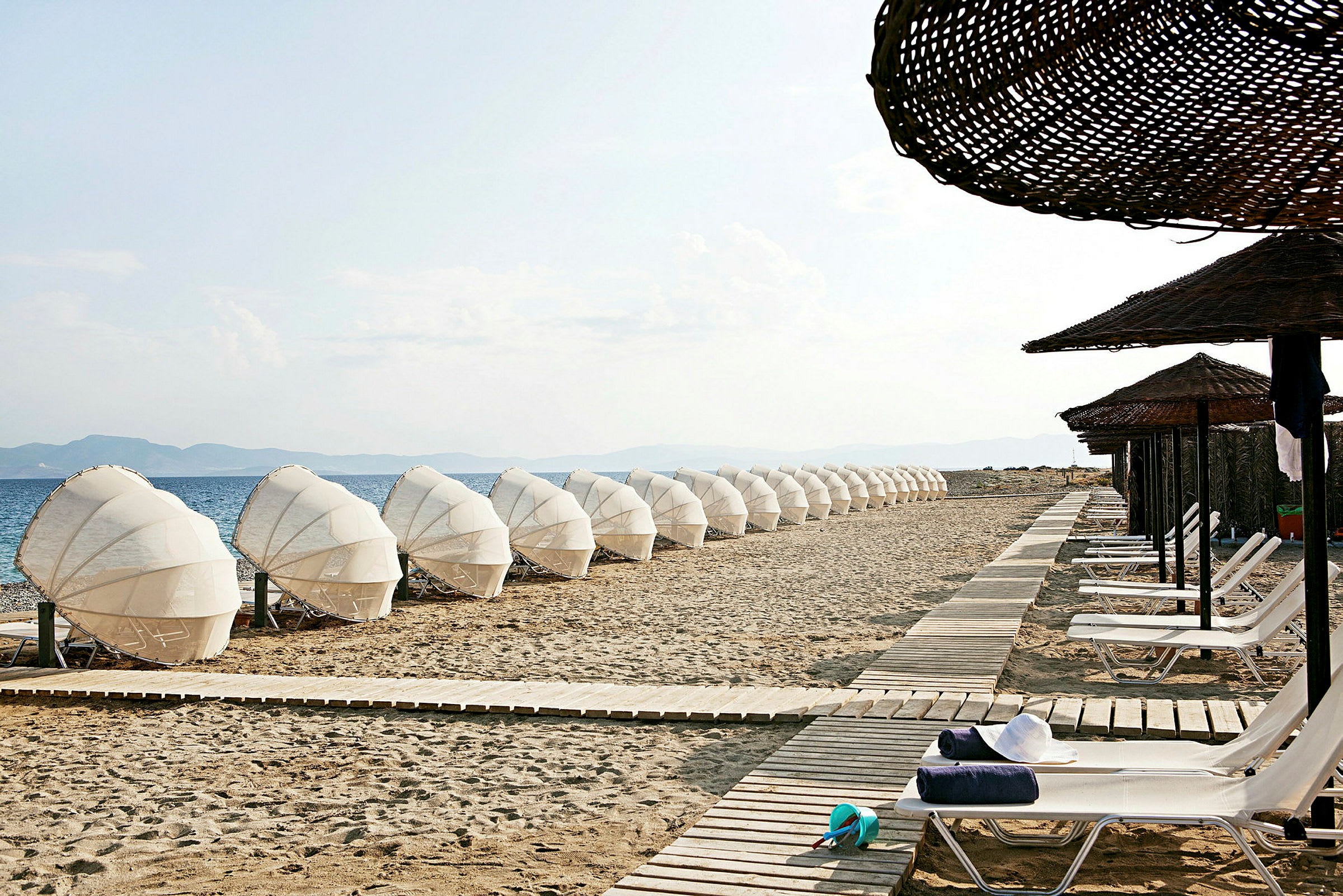 En strand med solstolar och parasoller längs en gångstig. (AI-genererad text)