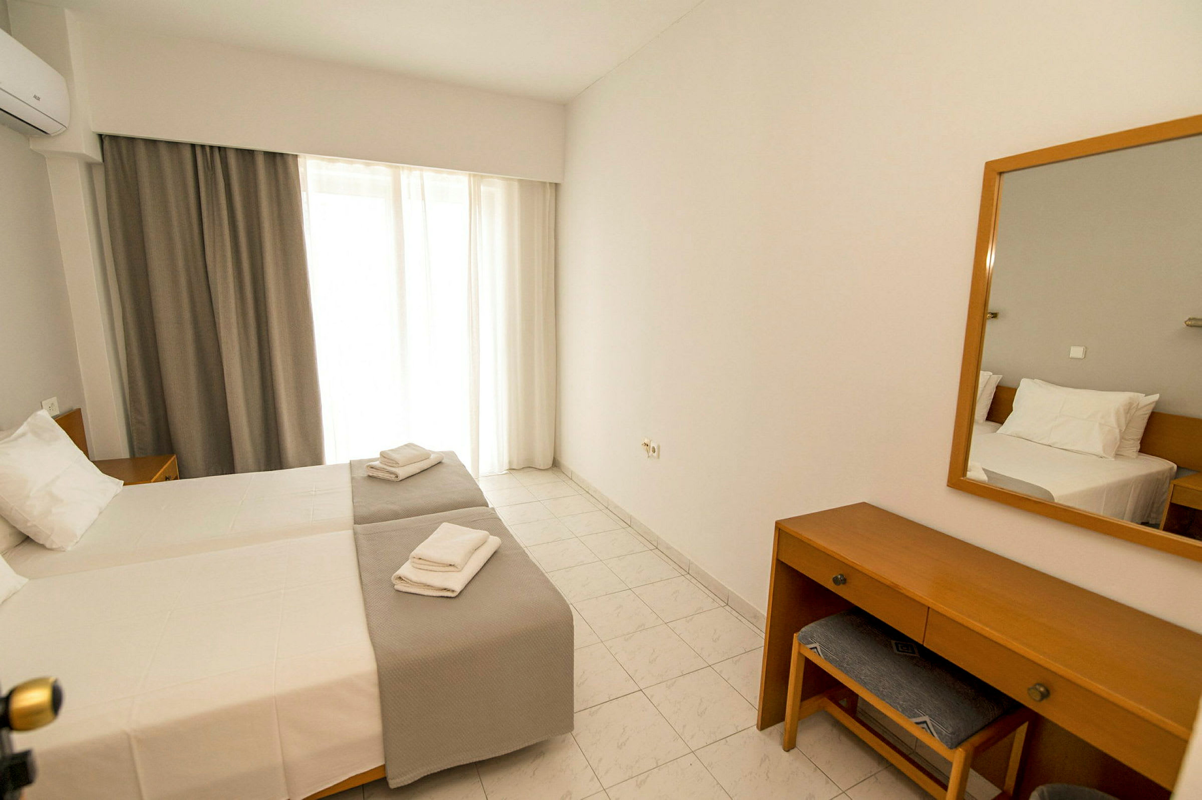 Ett hotellrum med två enkelsängar, ett skrivbord med stol och en spegel. (AI-genererad text)