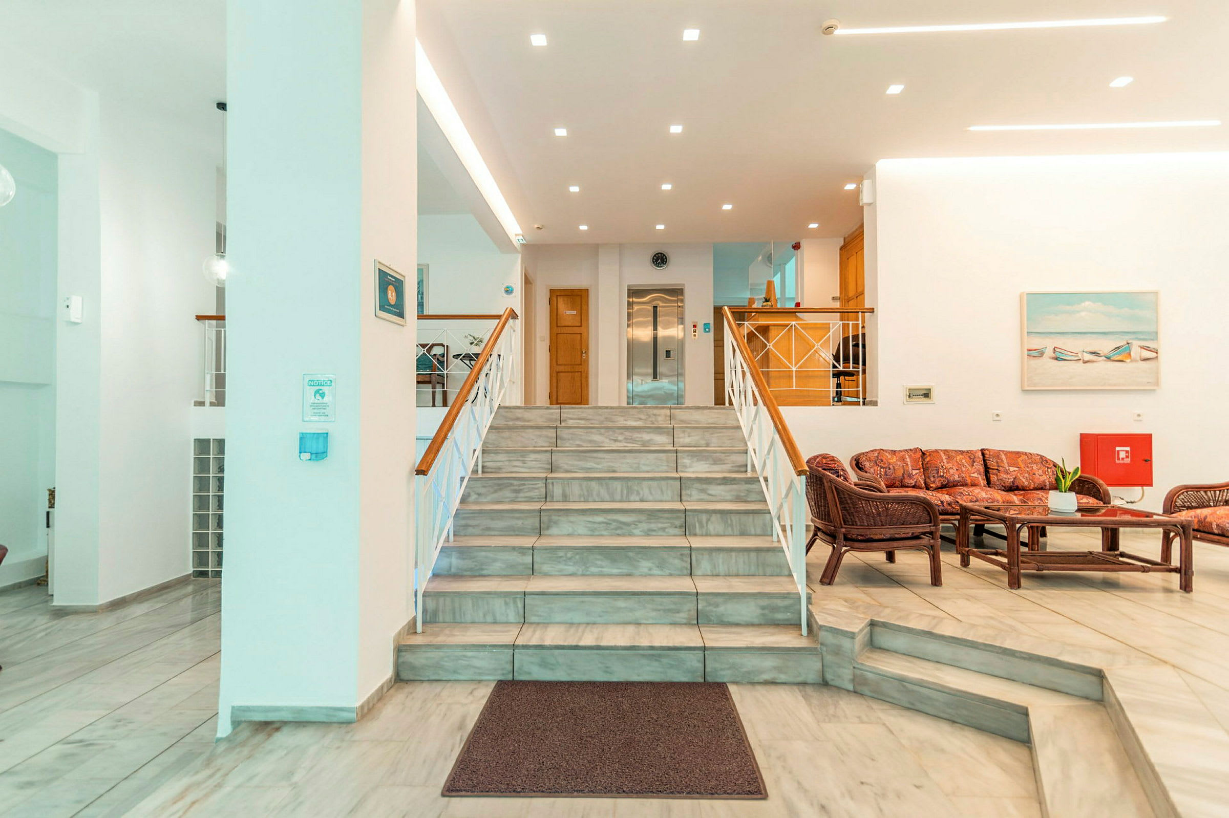 Hotellets lobby med en trappa, sittgrupp och reception. (AI-genererad text)