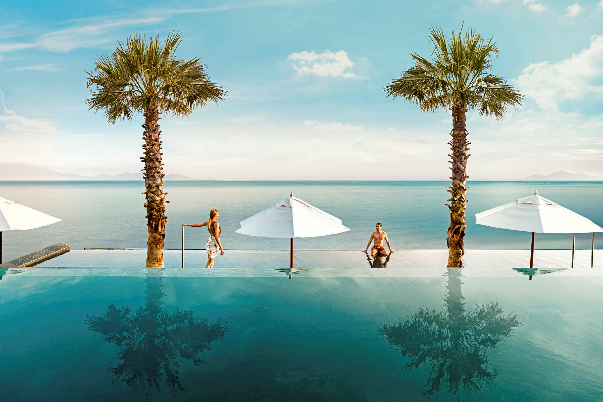 Bild av en infinitypool vid havet, med palmer och vita parasoller. (AI-genererad text)