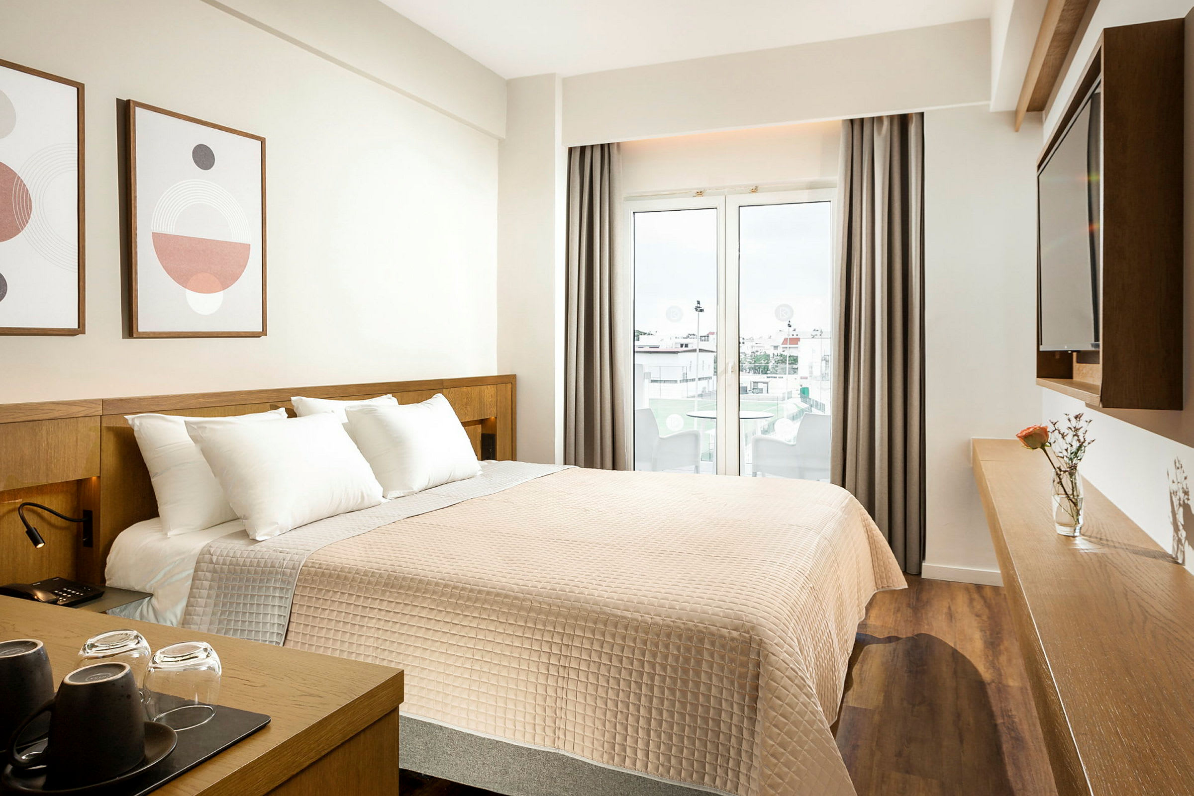 Hotellrum med en dubbelsäng, utsmyckning på väggen, och en glasdörr som leder till en balkong. (AI-genererad text)