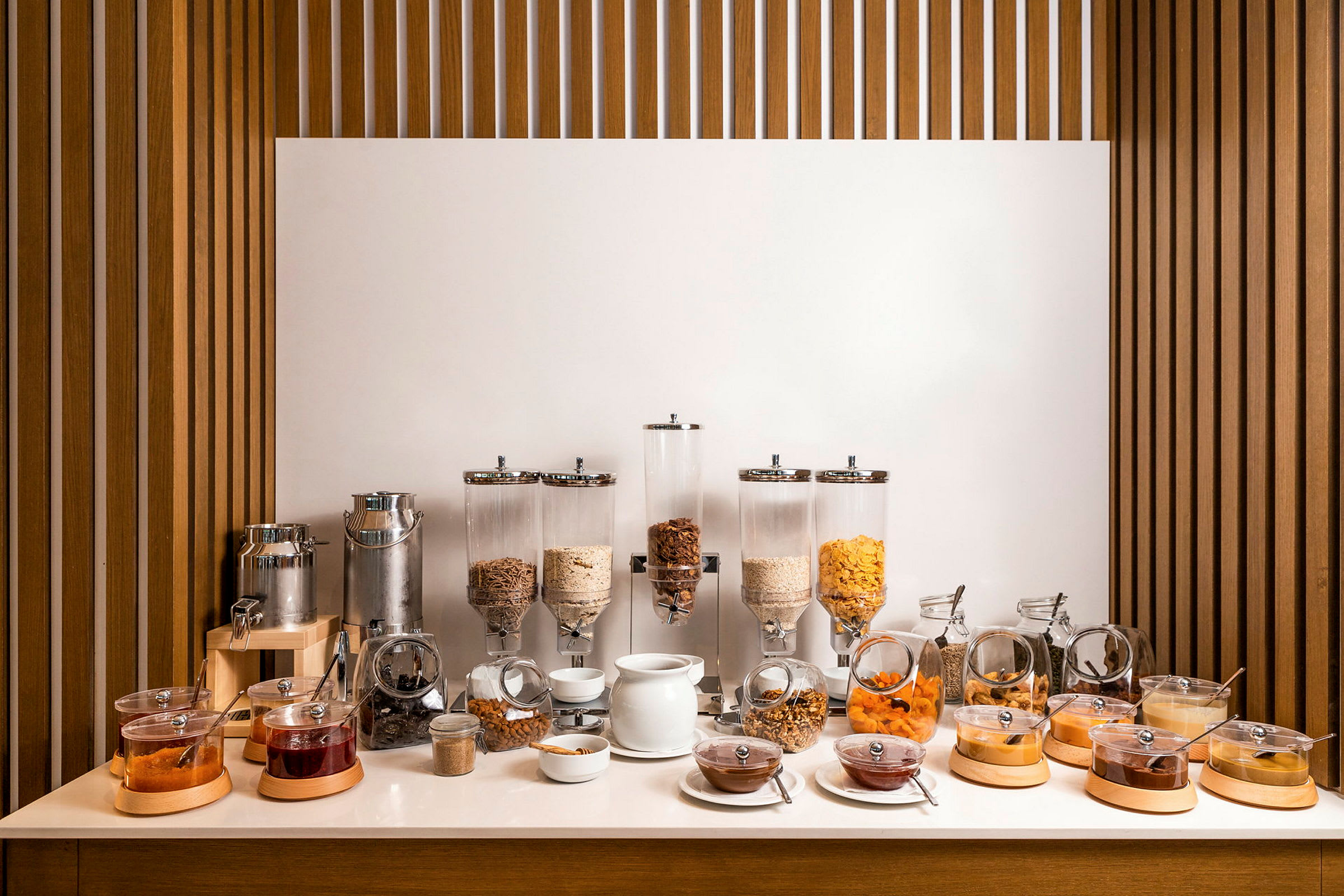 En frukostbuffé med olika flingor, torkad frukt, sylt och vätskeautomat. (AI-genererad text)