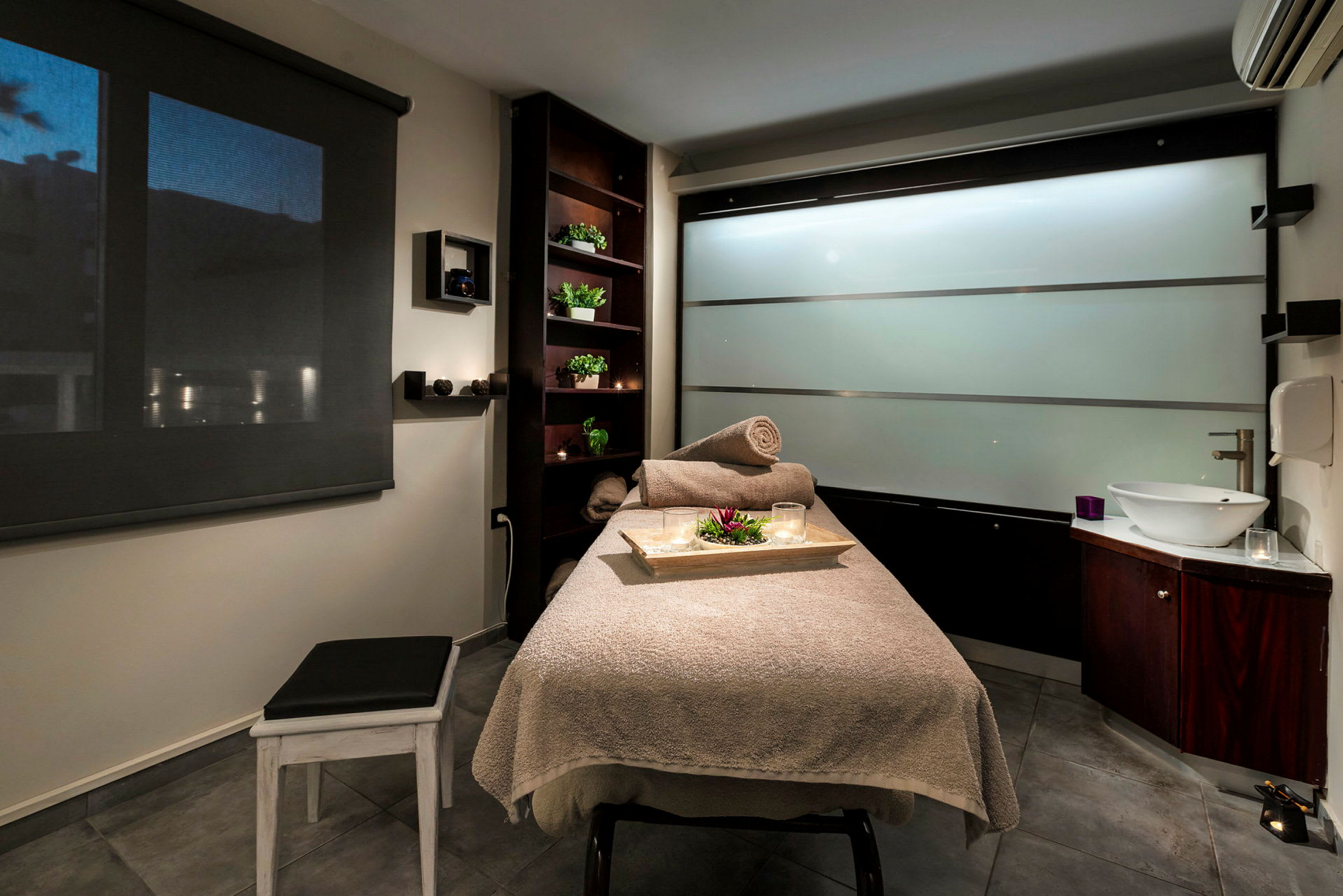 Ett rum för massage med en bädd täckt med handdukar och en bricka med dekorationer. (AI-genererad text)