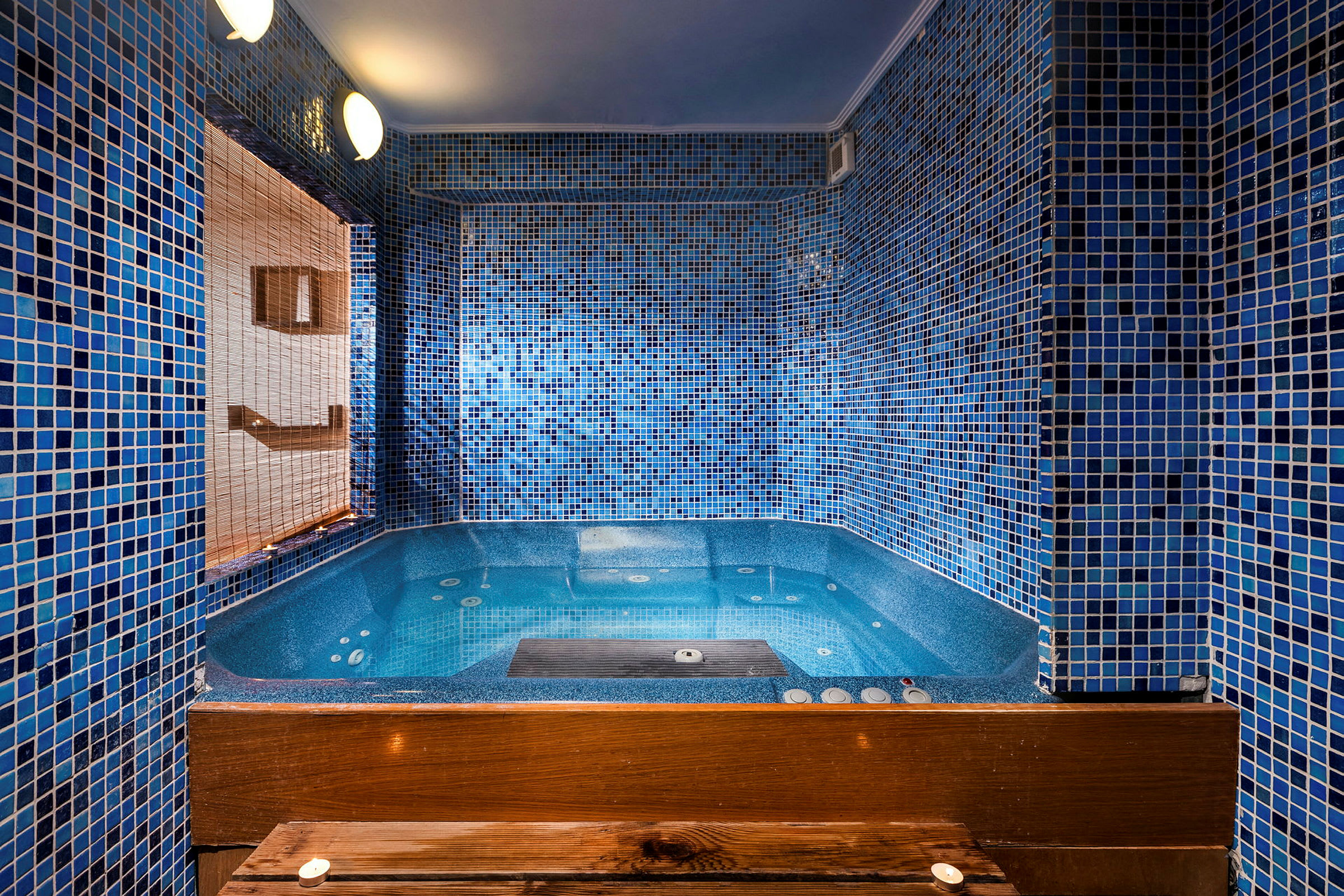 En bubbelpool inomhus med blå mosaikväggar. (AI-genererad text)
